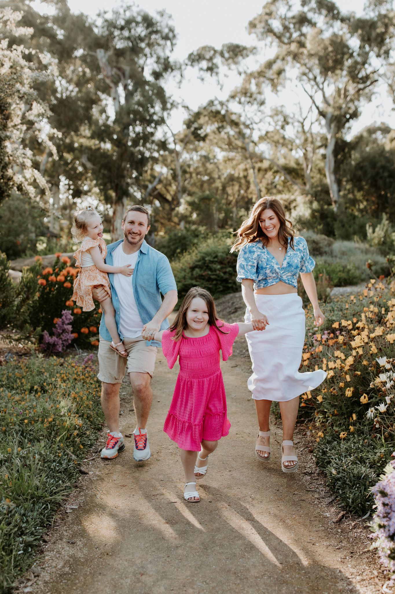 A family laughs and runs through Wittunga Garden in Blackwood during a family photography session with Lauren Lunn Photography.