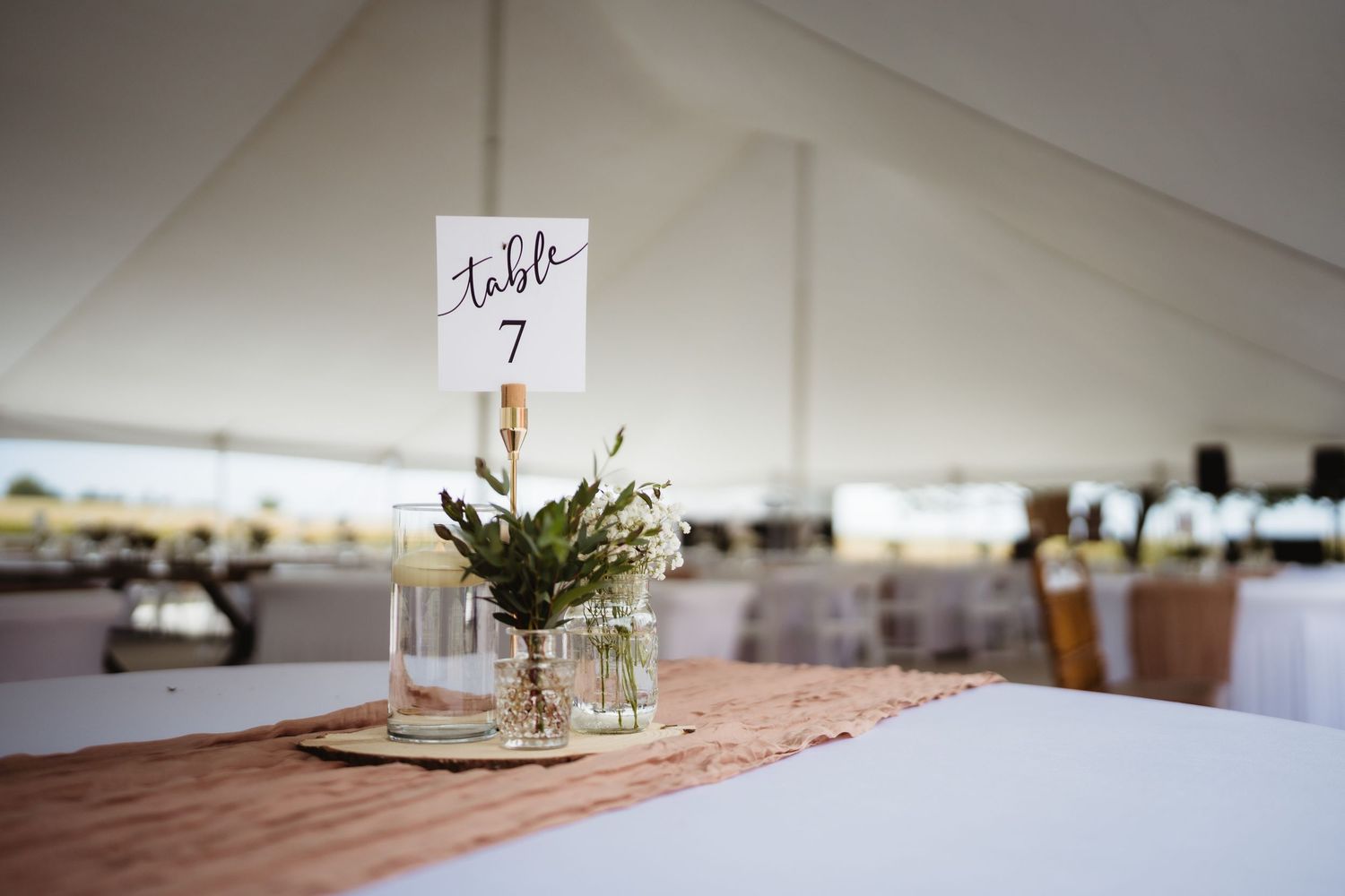 A series of white-clothed tables set up for an elegant wedding reception with delicate floral centerpieces.