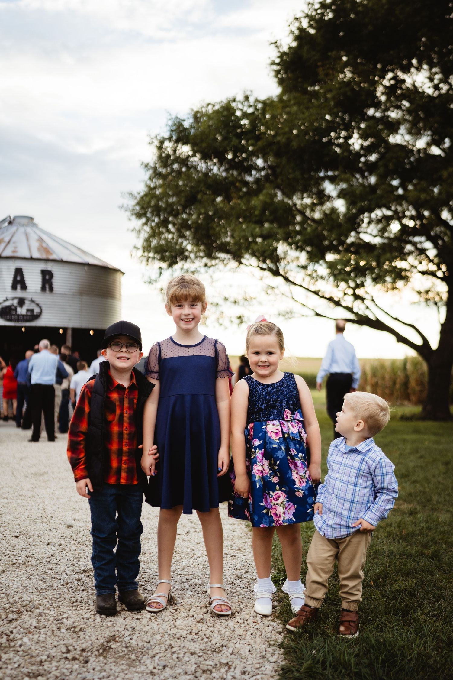 A series of low-angle photos showing children's legs and feet standing together on a grassy outdoor path at sunset.