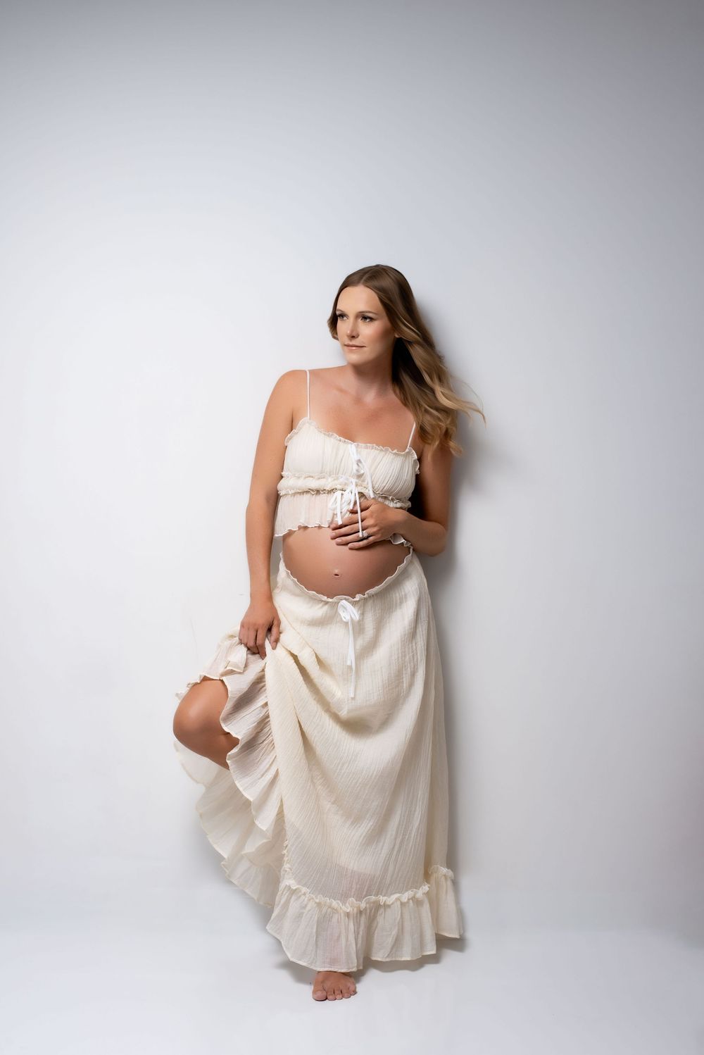 Glamorous pregnancy photoshoot in elegant studio setting.