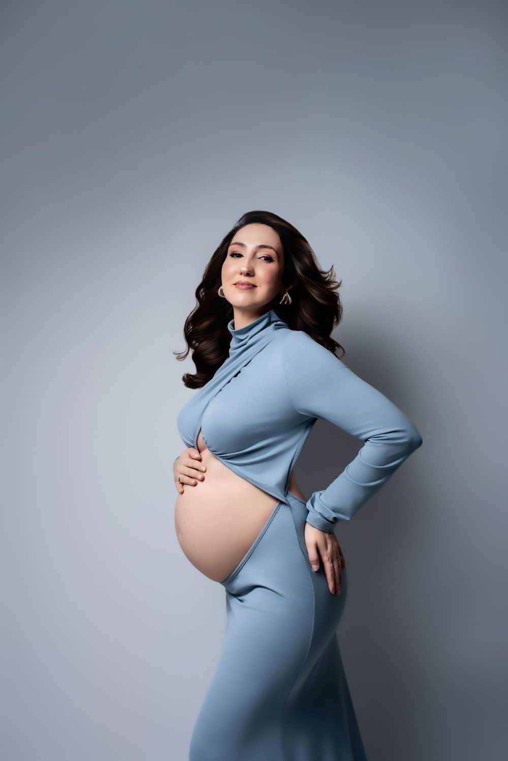 Elegant maternity portrait of a pregnant woman in a silk gown.