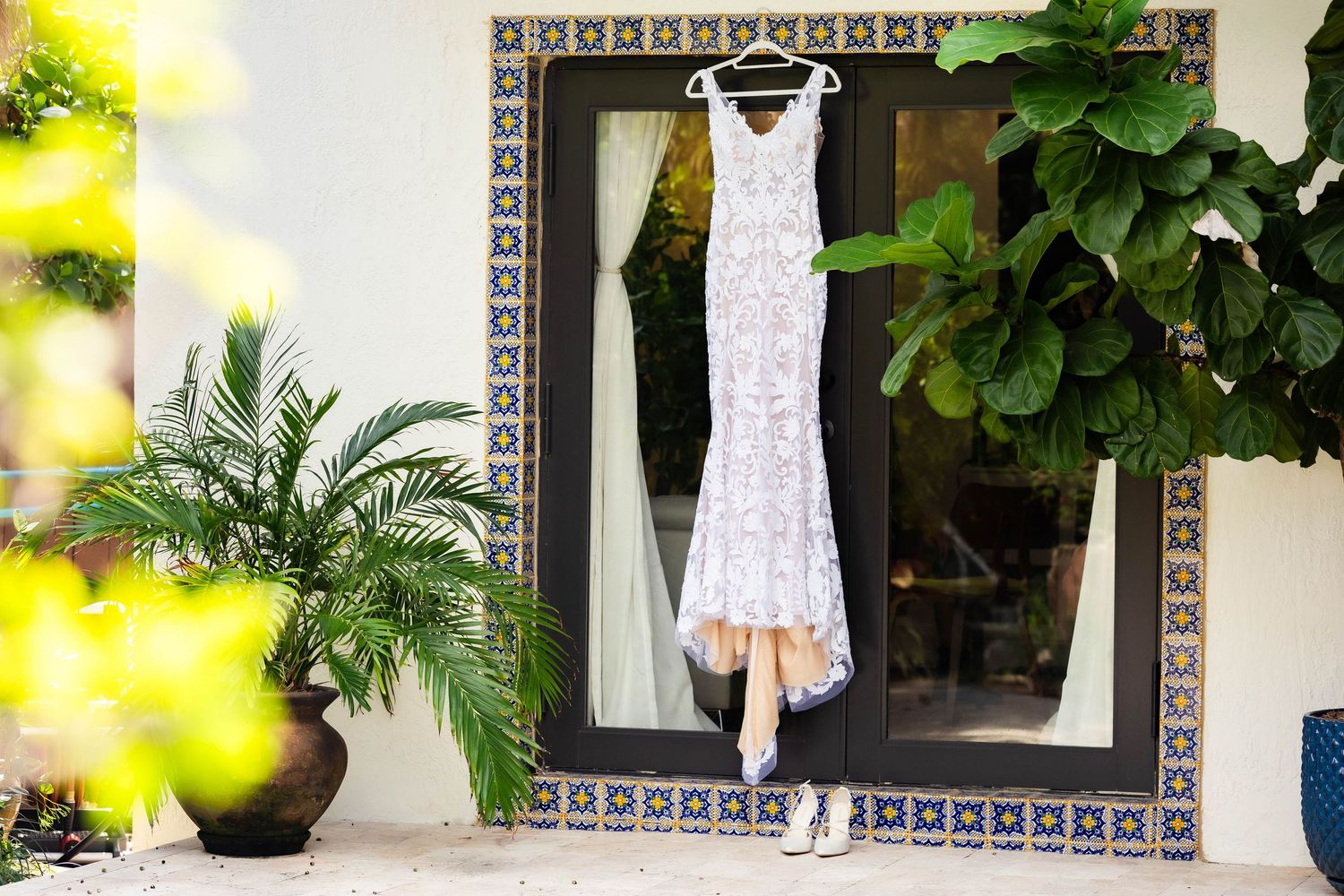 Bright sunlit outdoor venue with Spanish-style architecture and tropical foliage.