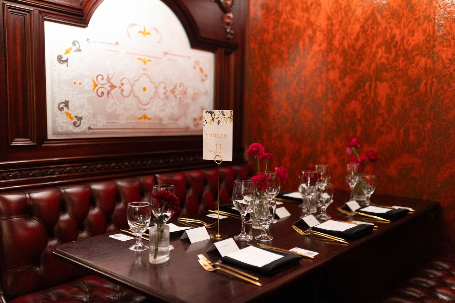 Upscale dining room with red damask walls and formal place settings arranged for an elegant event.