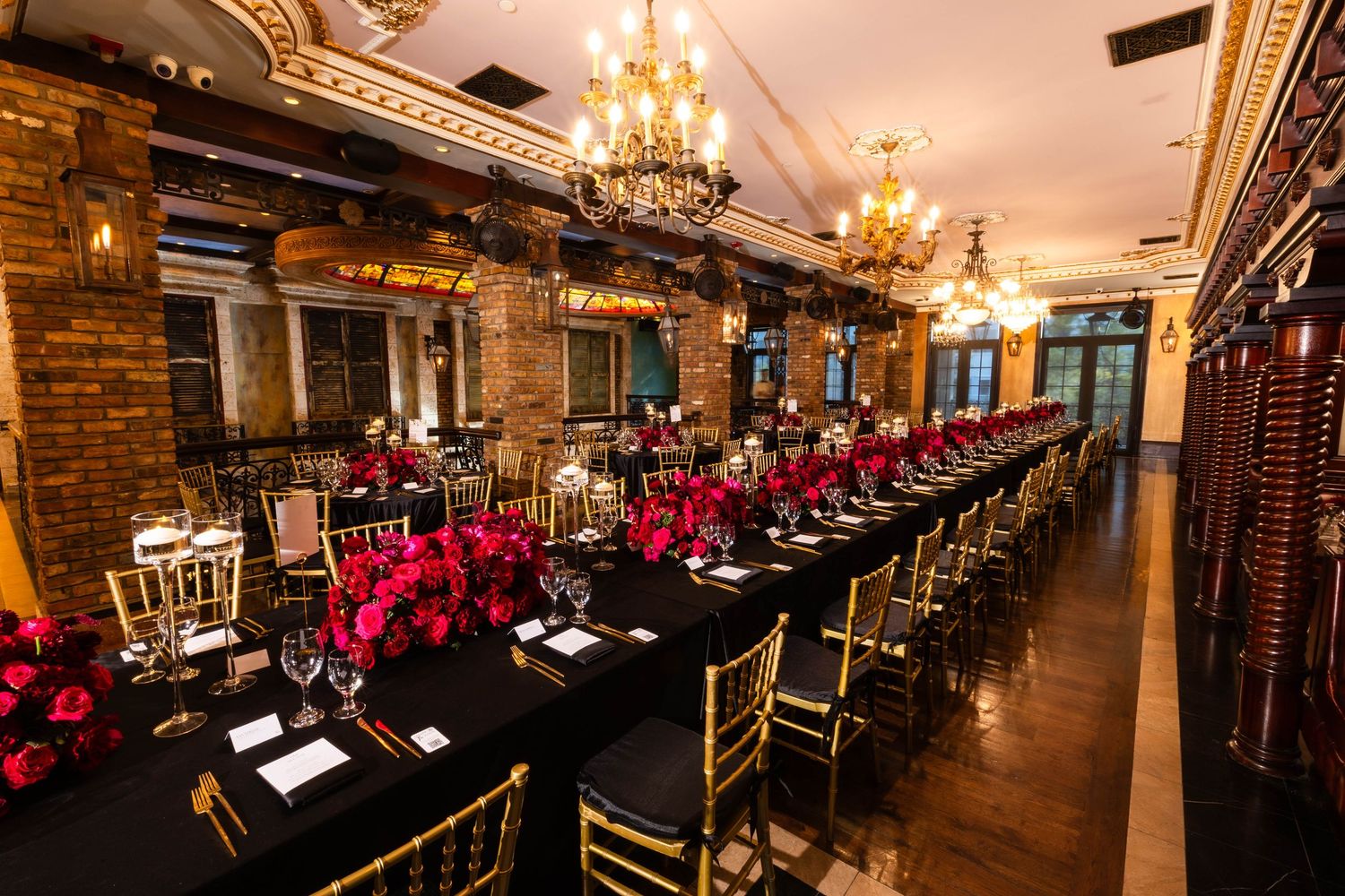 Panoramic view of a luxurious banquet hall with gold chandeliers, wooden floors and ornate table settings.