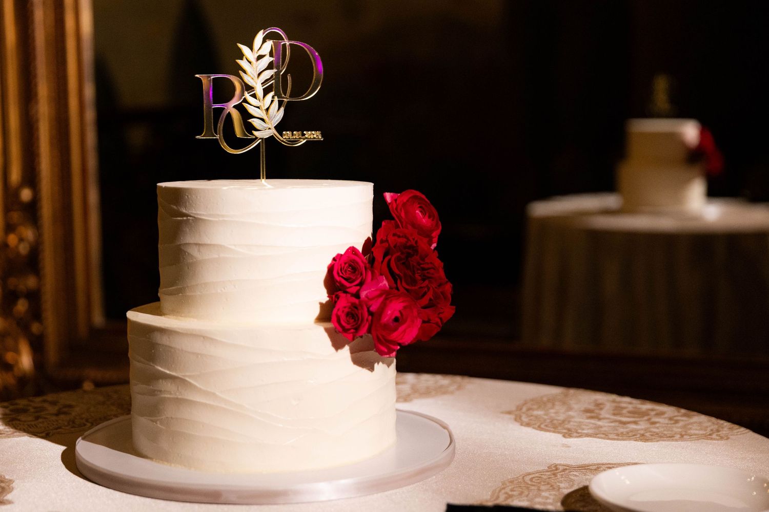 White tiered wedding cake decorated with delicate floral details displayed at an elegant reception.