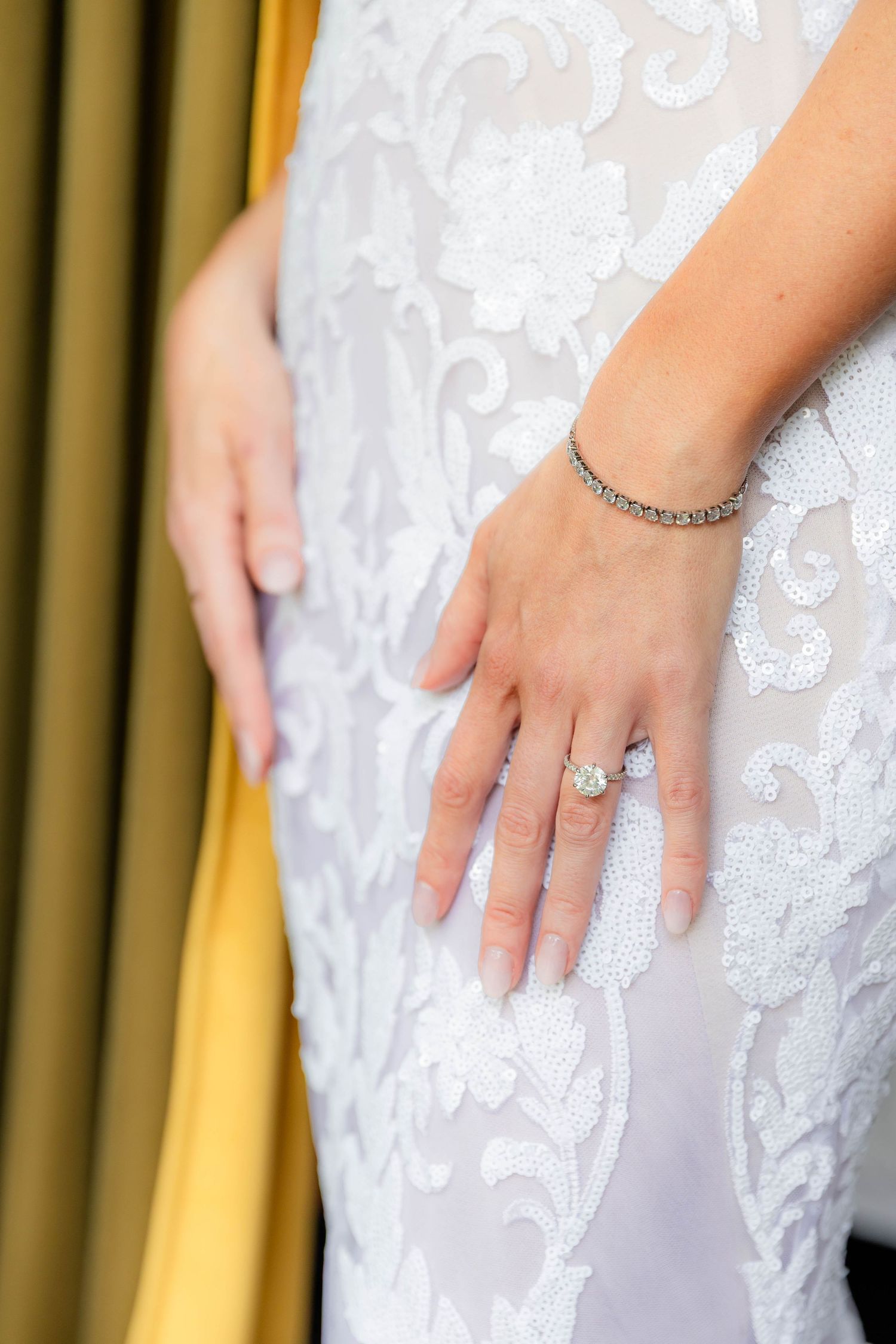 Close-up of bridal jewelry and lace detail on wedding dress.