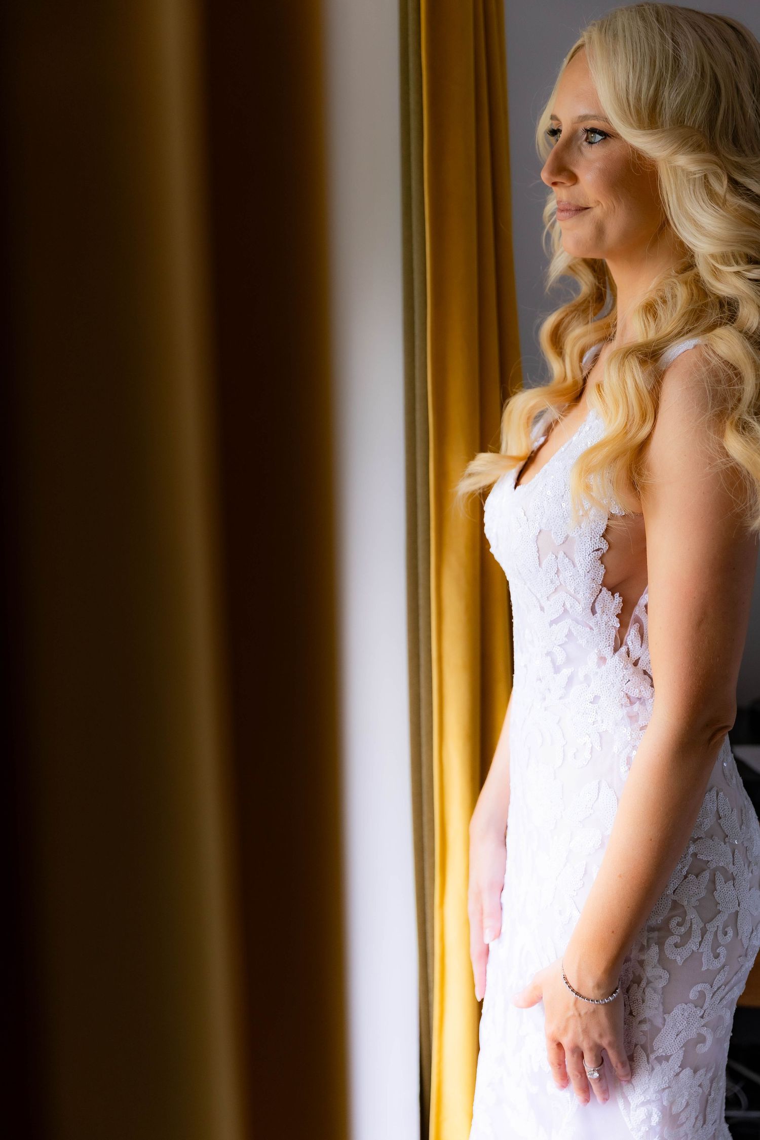 Elegant bridal portrait with lace dress against golden window light.