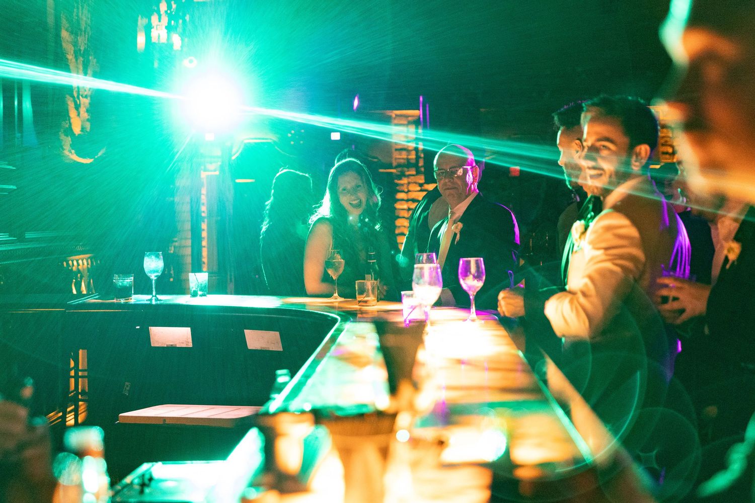 Wedding reception dance floor filled with green lighting and dancing silhouettes.