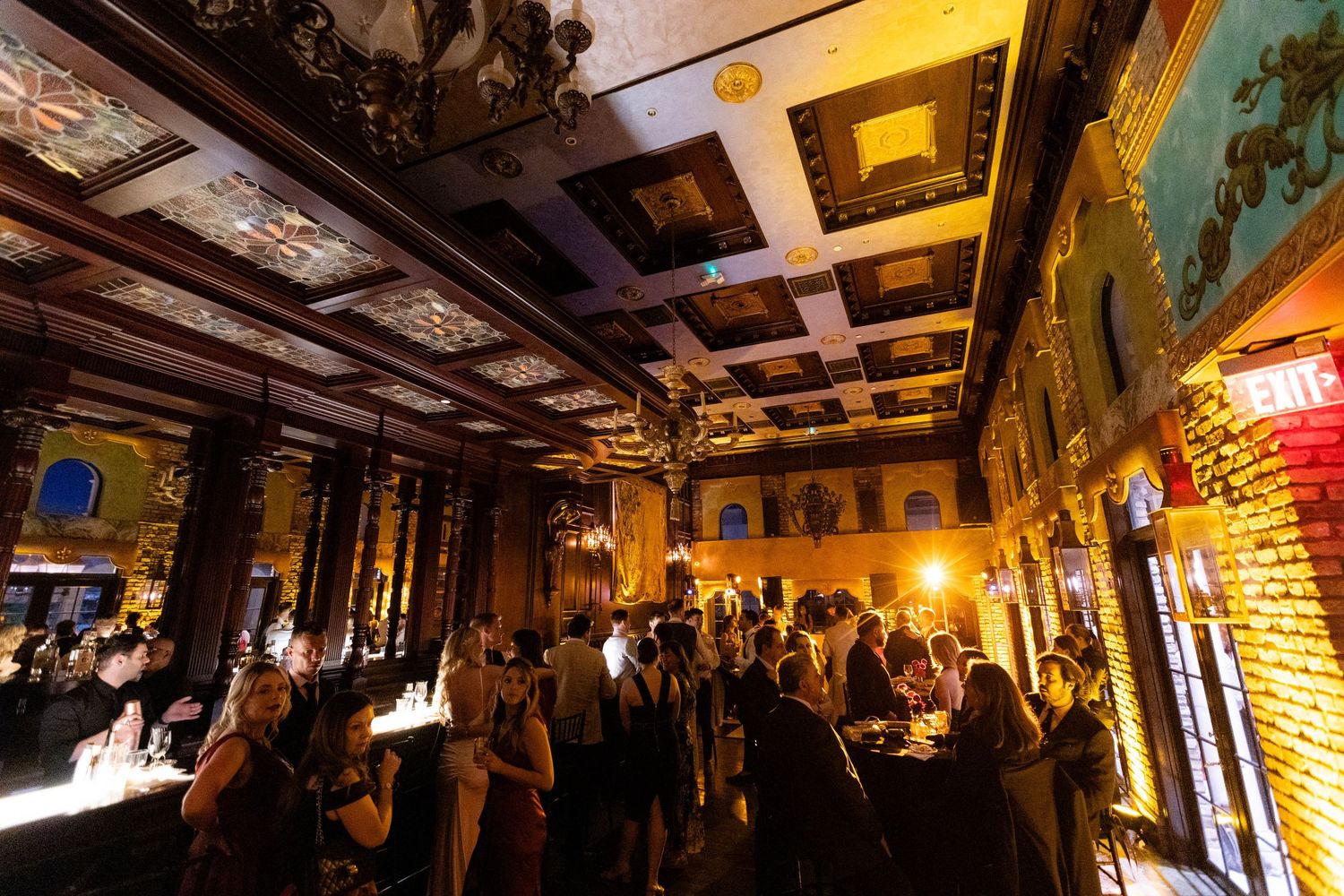 A dimly lit reception venue with ornate ceiling details and warm ambient lighting creates a romantic atmosphere.