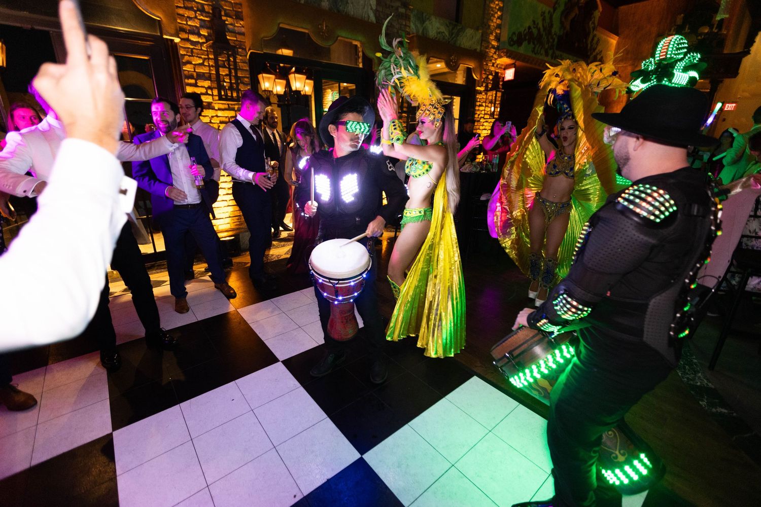 Colorful dance party with guests raving under neon green and purple lighting effects.