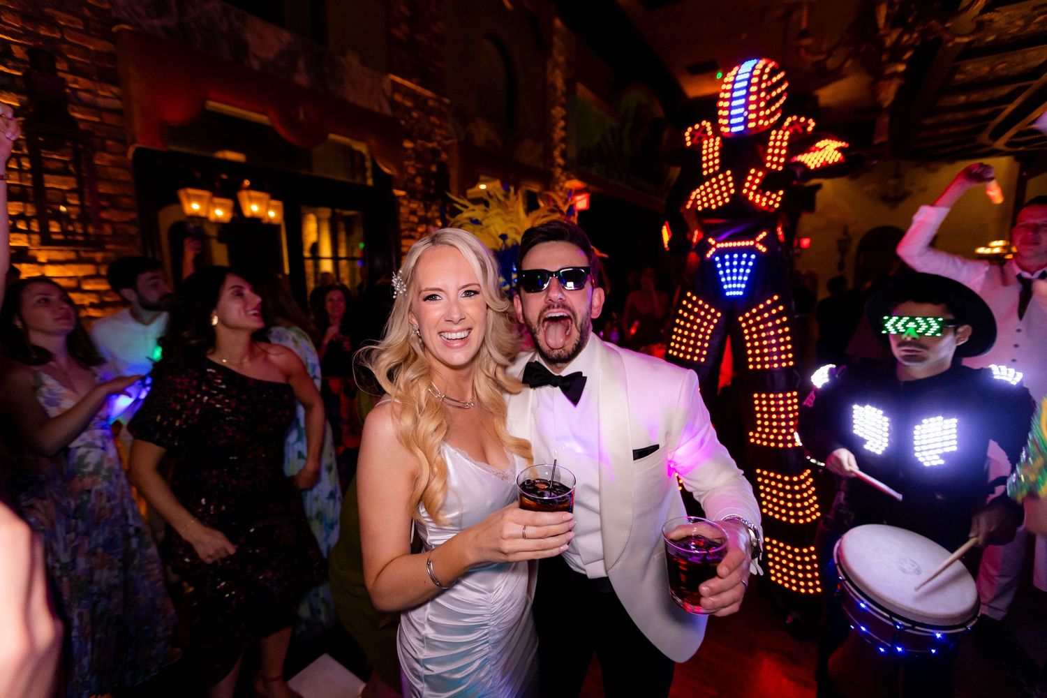 Wedding reception dance floor filled with guests celebrating under bright LED lighting displays.