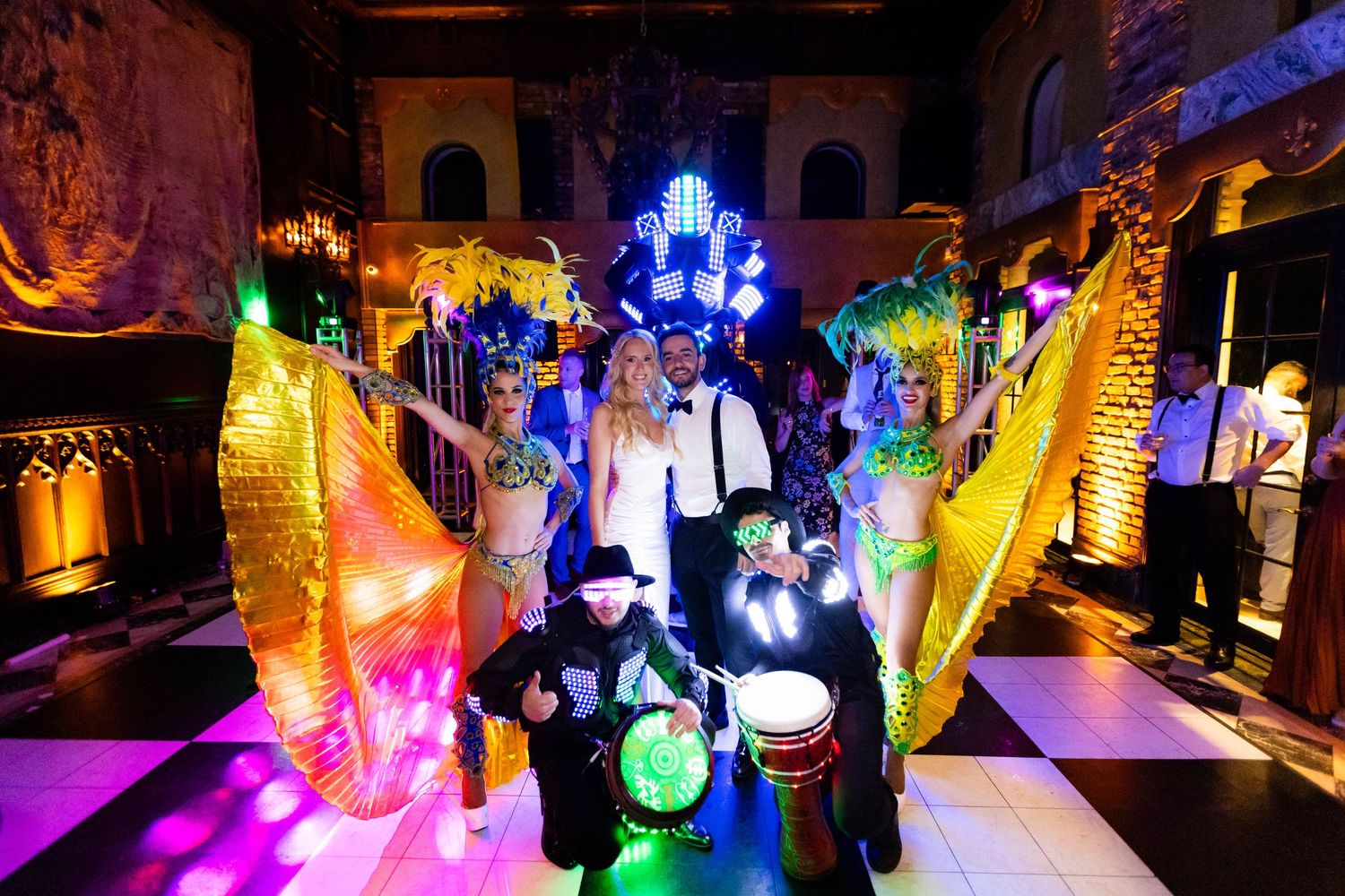 Colorful LED lights illuminate a dimly lit wedding reception venue creating a vibrant party atmosphere.