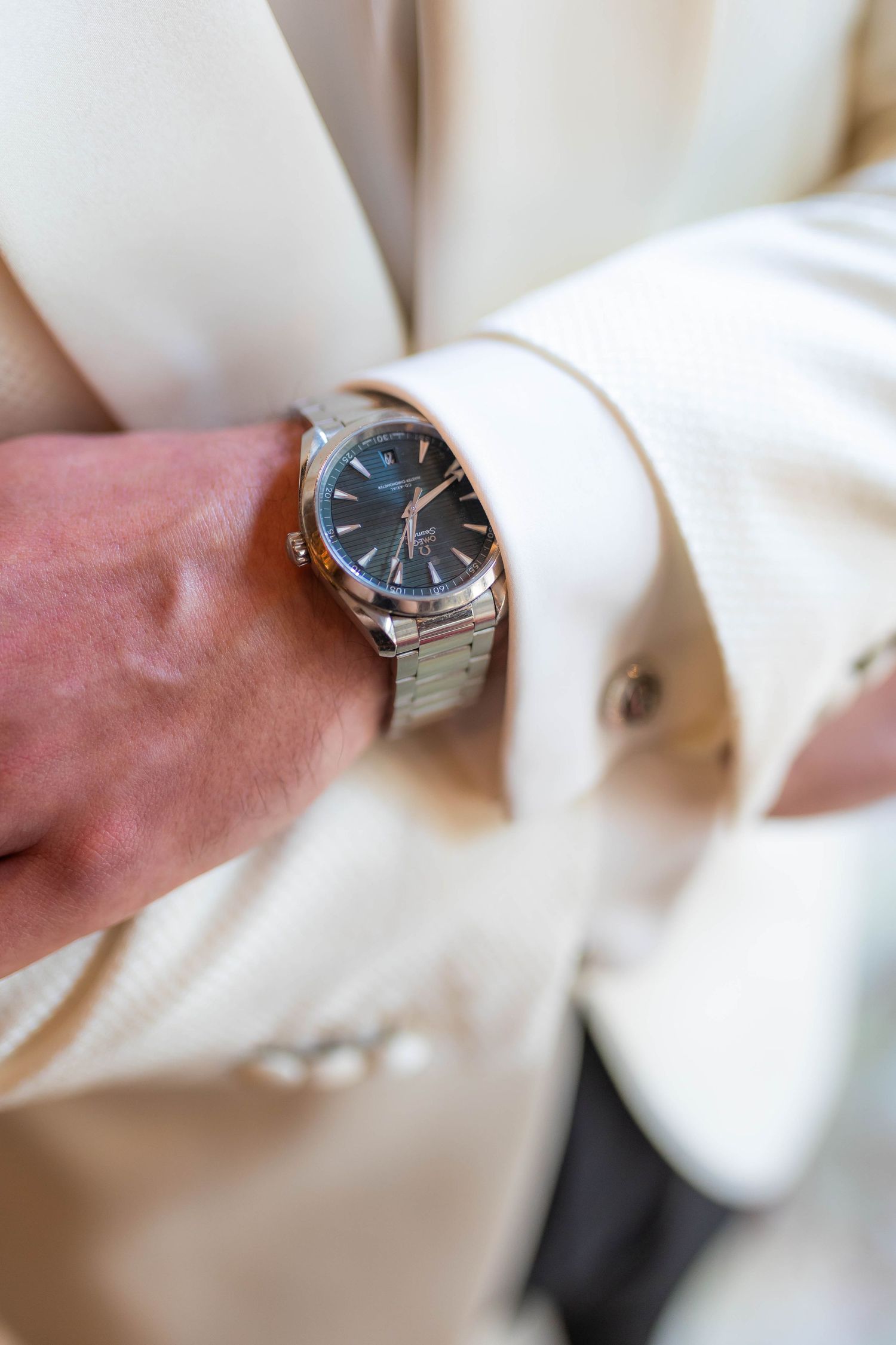Close-up detail shot of a silver wristwatch on formal white sleeve cuff.