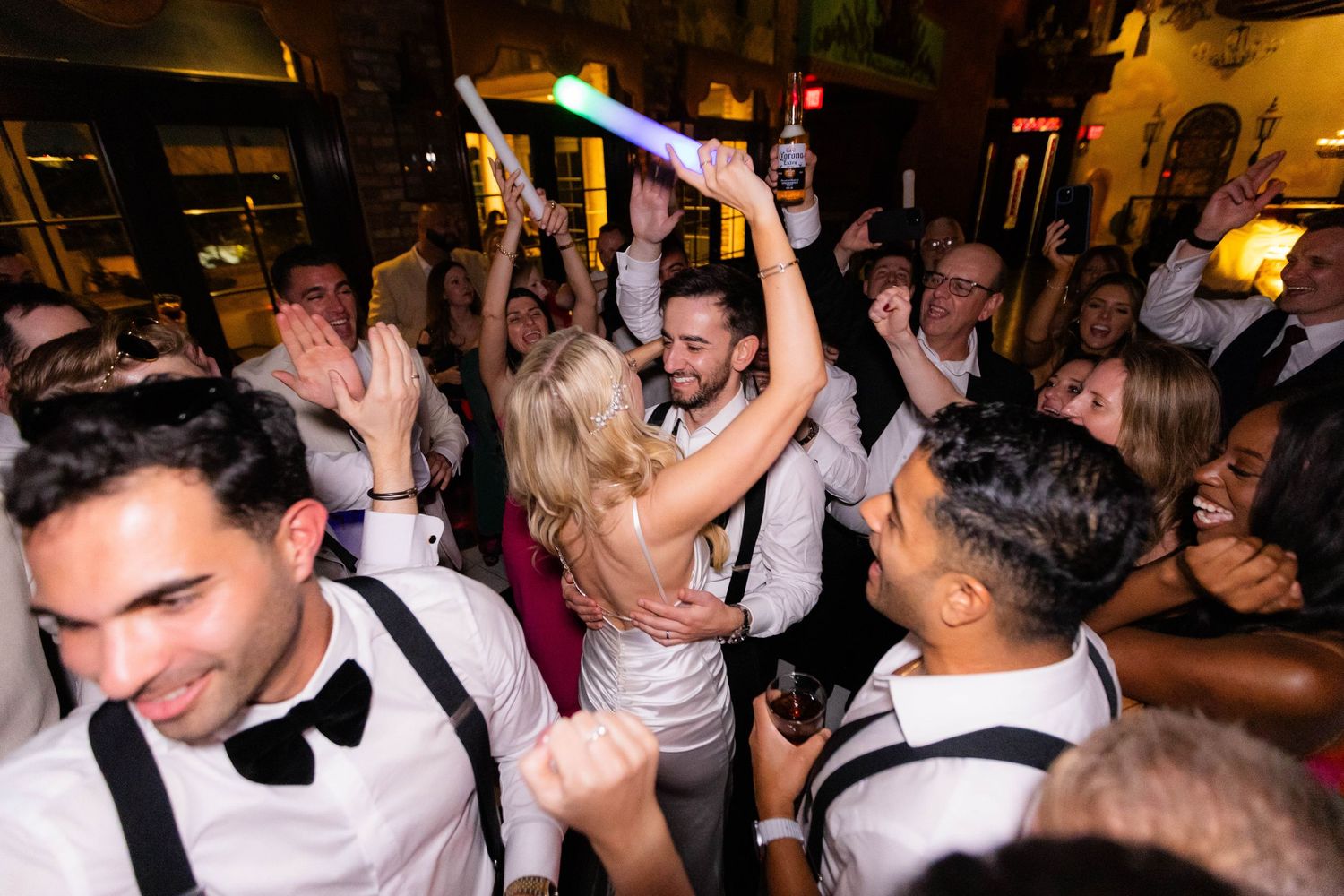 Wedding reception dance floor packed with guests celebrating in formal attire.