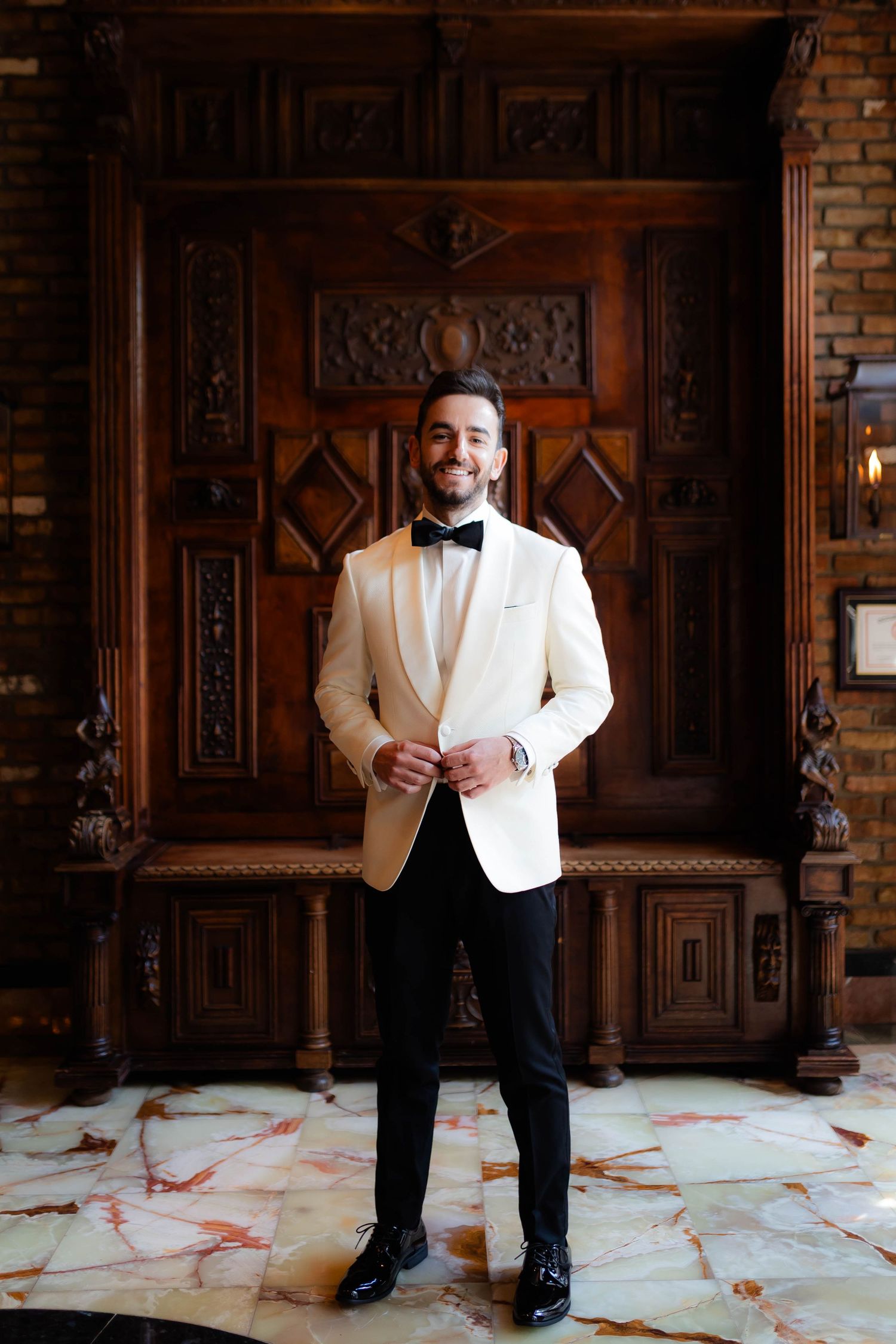 Portrait sequence of a groom in white dinner jacket posing against dark wooden paneling.