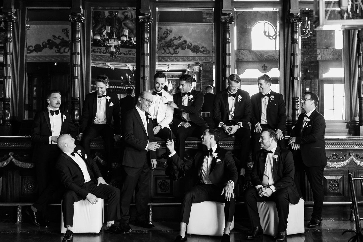 Black and white photo of formal wedding party in classic venue.