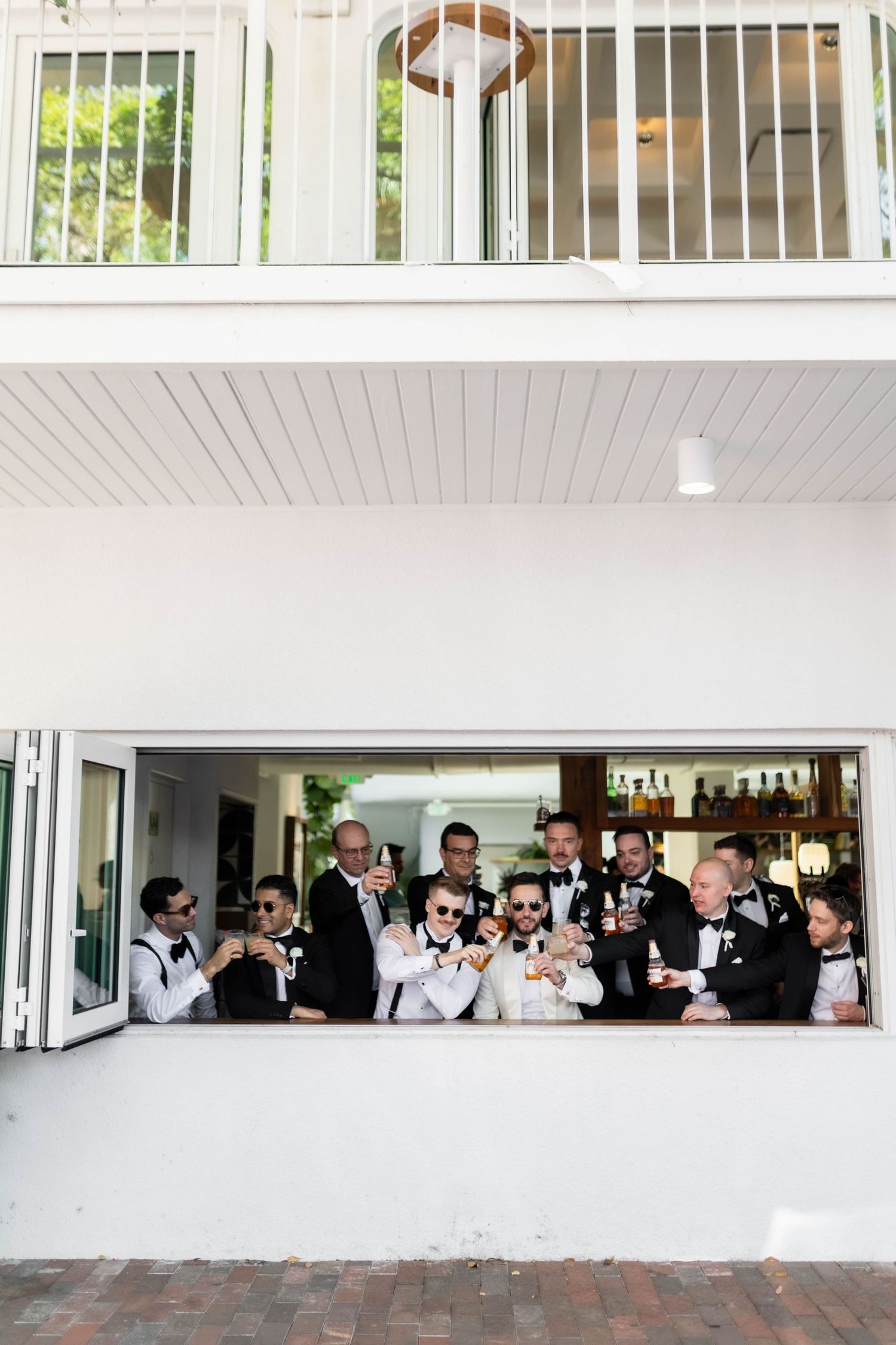 A panoramic view of wedding guests mingling in a modern white venue with large windows.