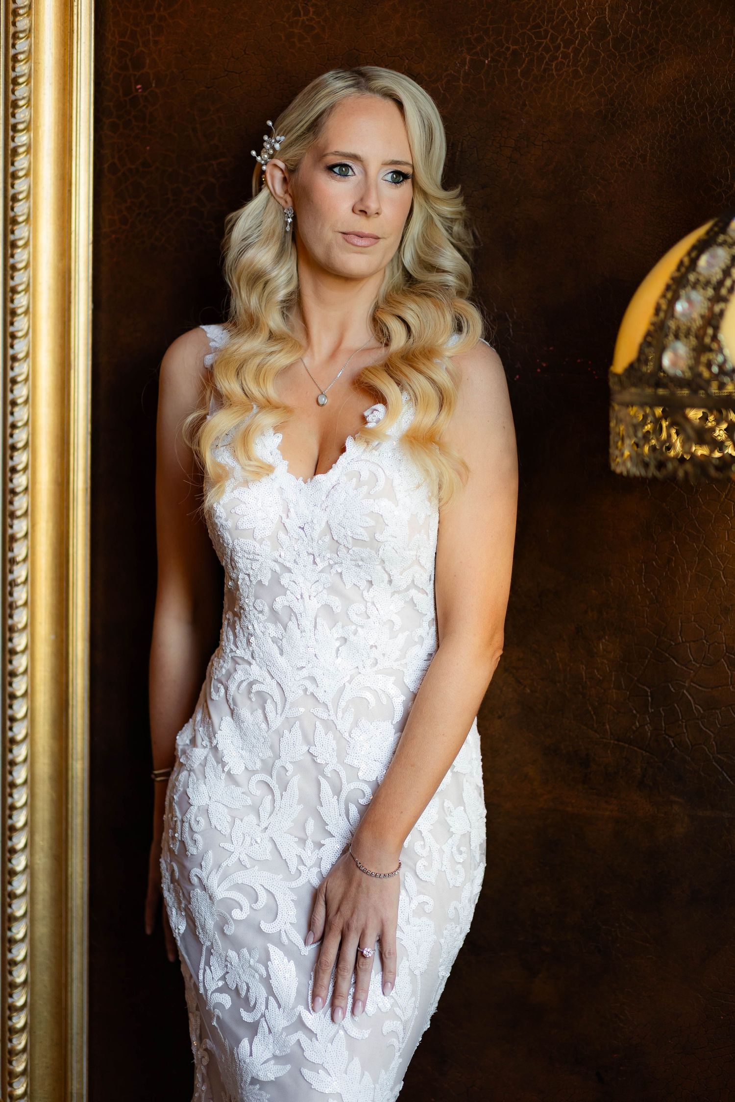 Beautiful white lace wedding gown with intricate detailing shown against an elegant dark backdrop.