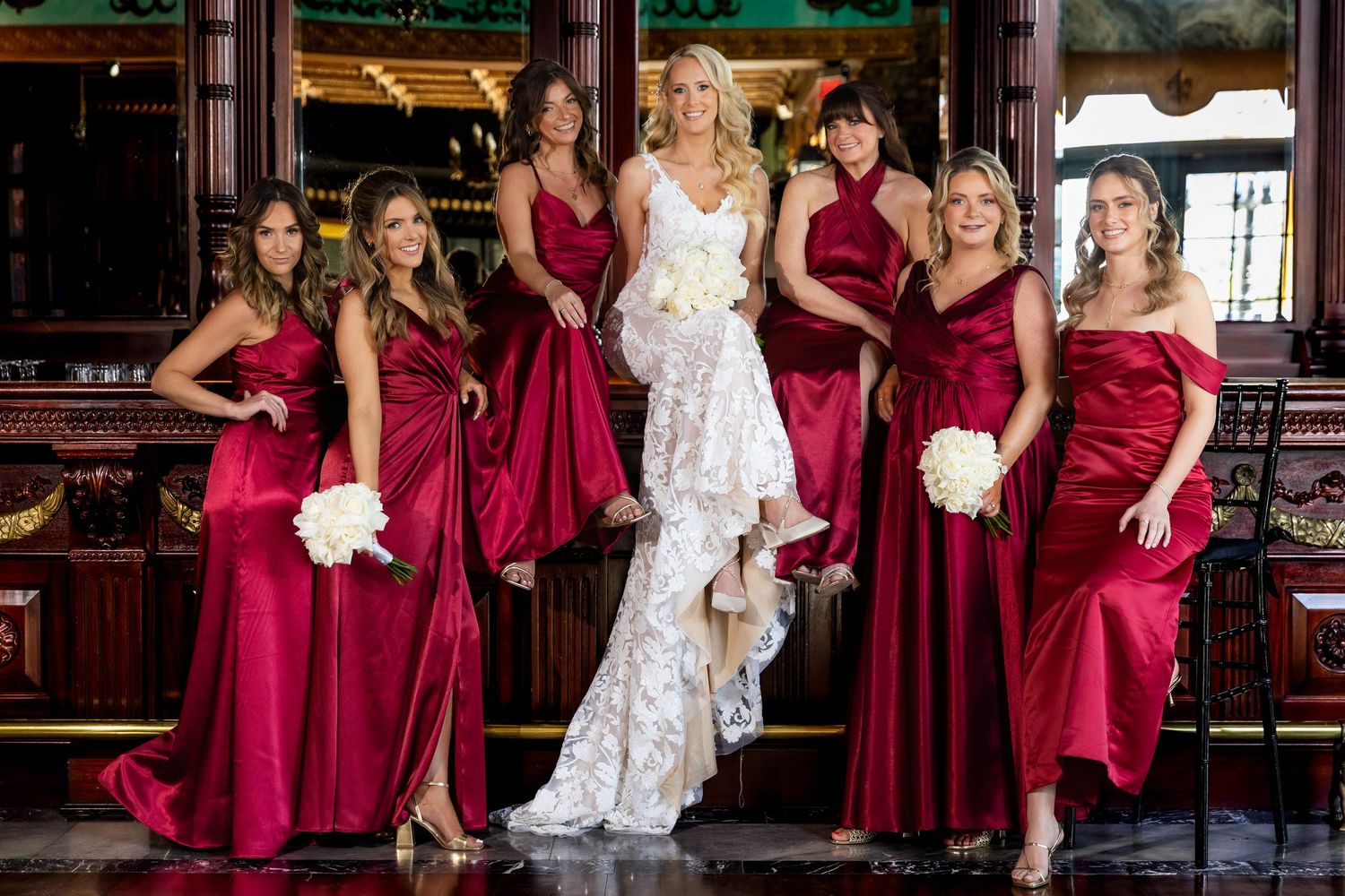 Wedding party with bridesmaids in burgundy dresses posing together.