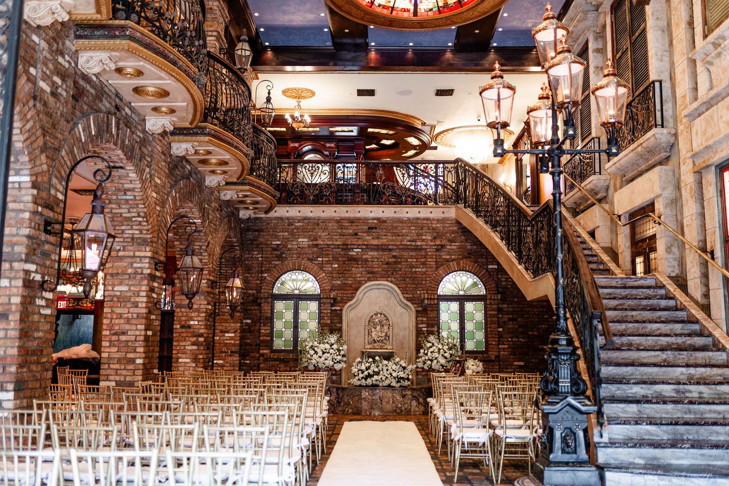 Panoramic view of a grand wedding ceremony space with stone walls and white chairs.