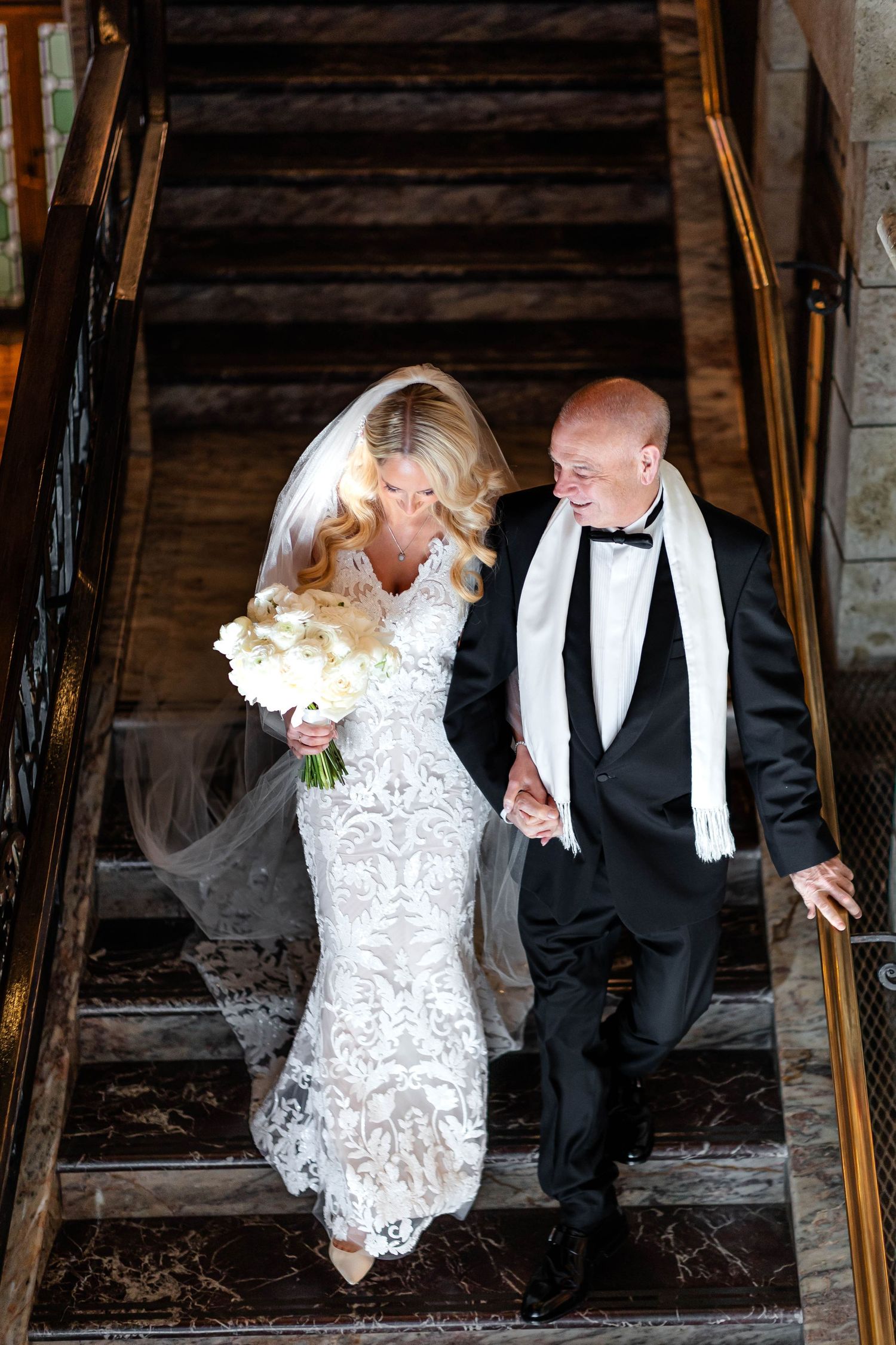 Couple descending rustic wooden staircase during wedding photoshoot.