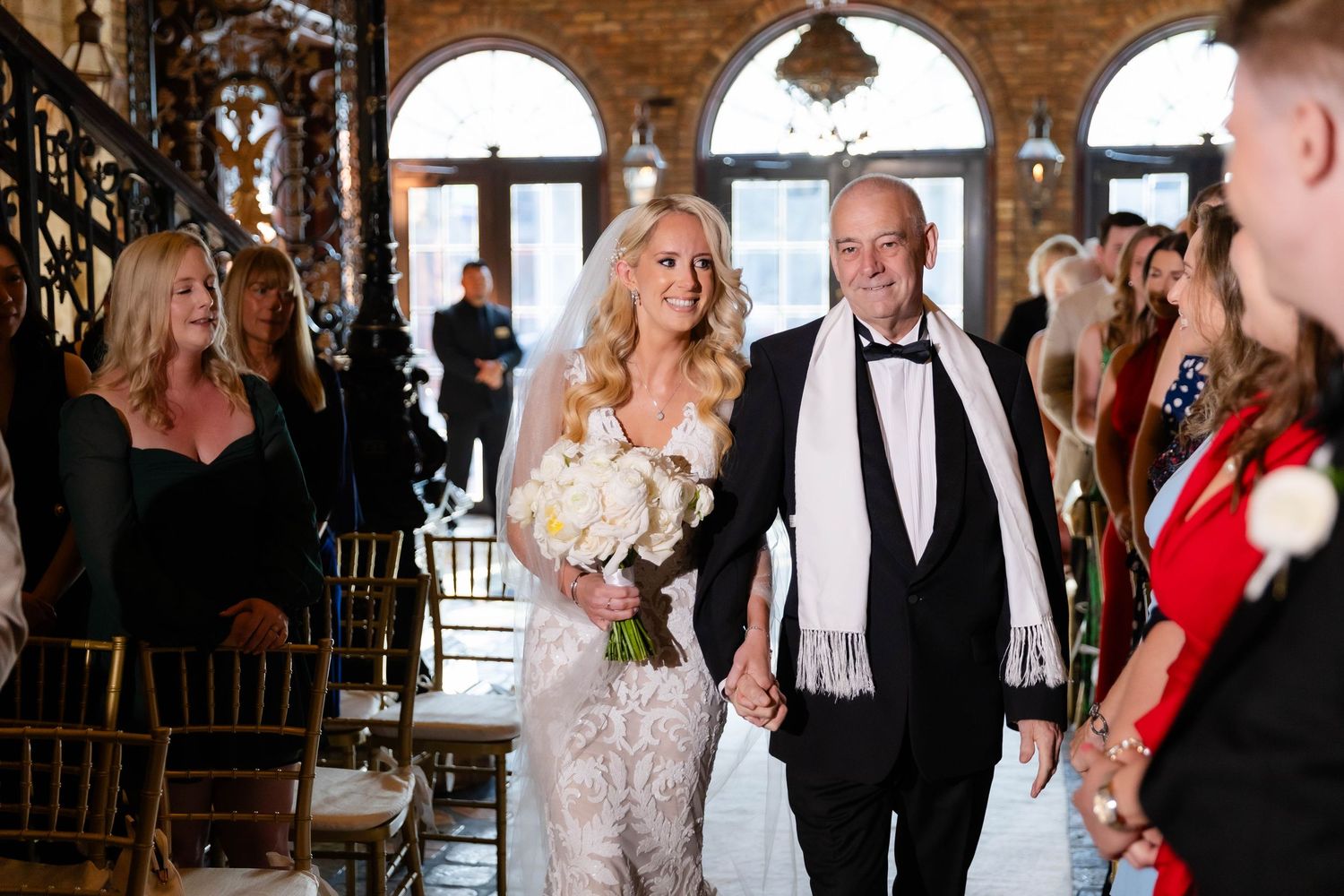 Wedding celebration with guests dancing and enjoying festivities in rustic brick-walled venue.