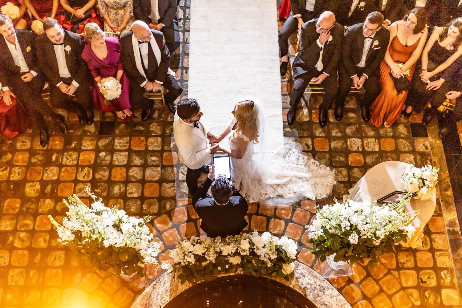 Overhead view of an elegant wedding reception with floral arrangements and guests seated at round tables.