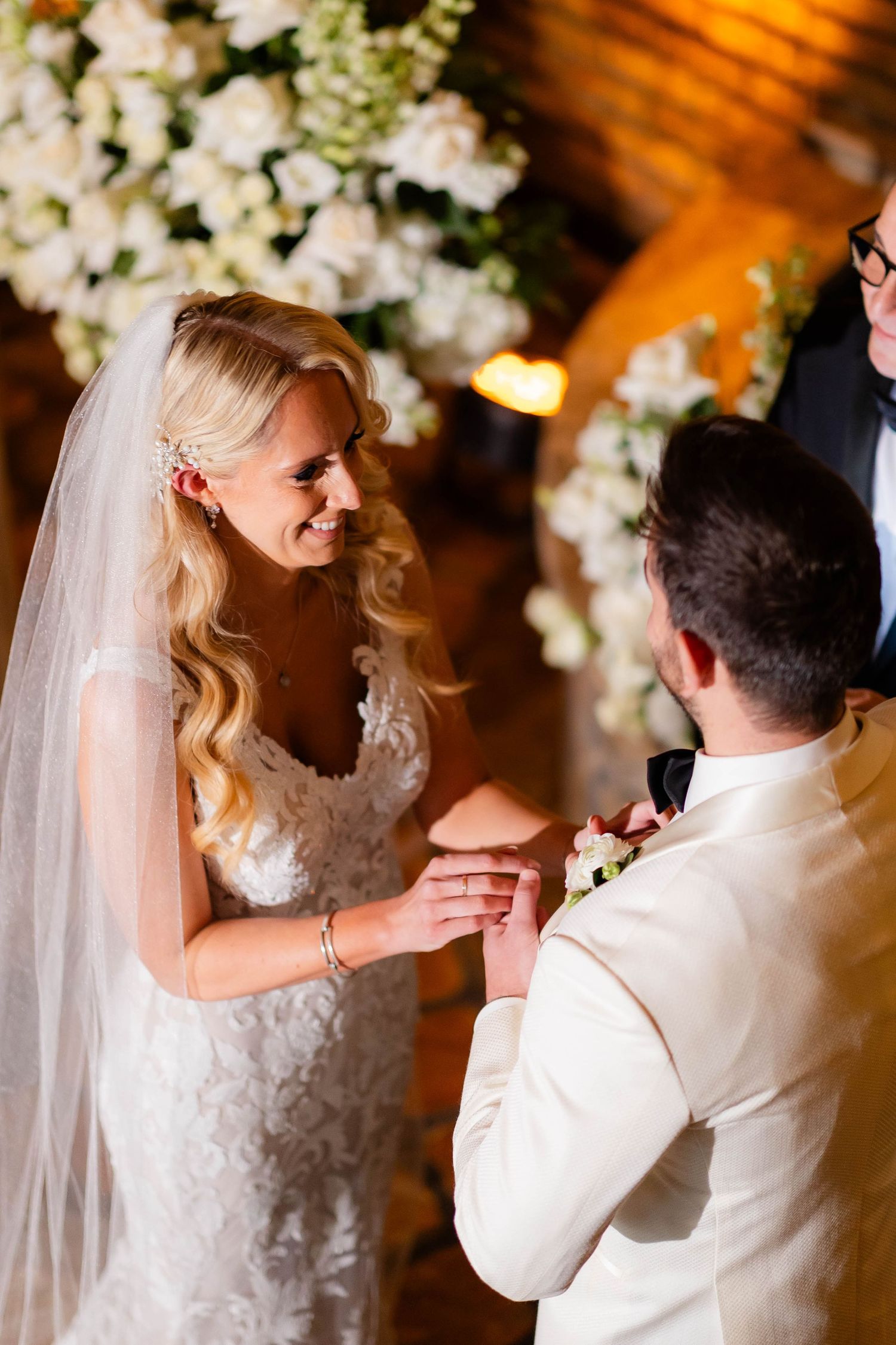 Couple shares their first dance under elegant white floral arrangements and warm lighting.