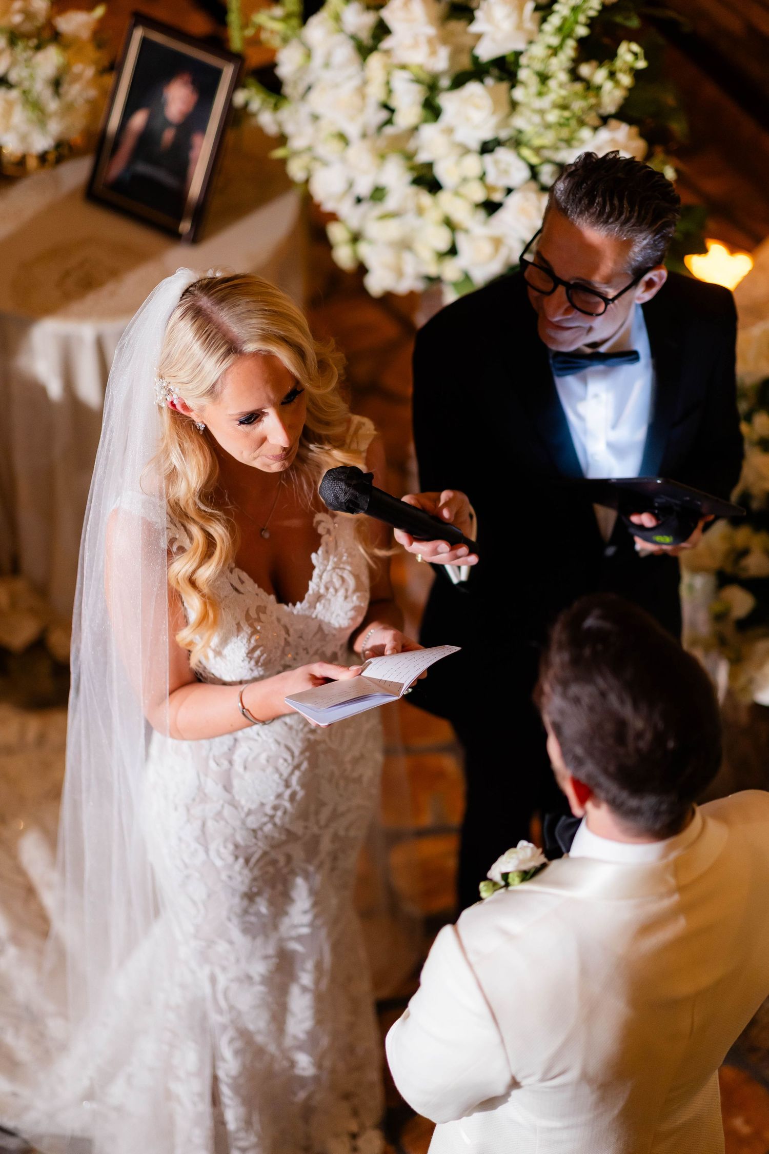 Elegant wedding ceremony with white floral arrangements and signing of documents.