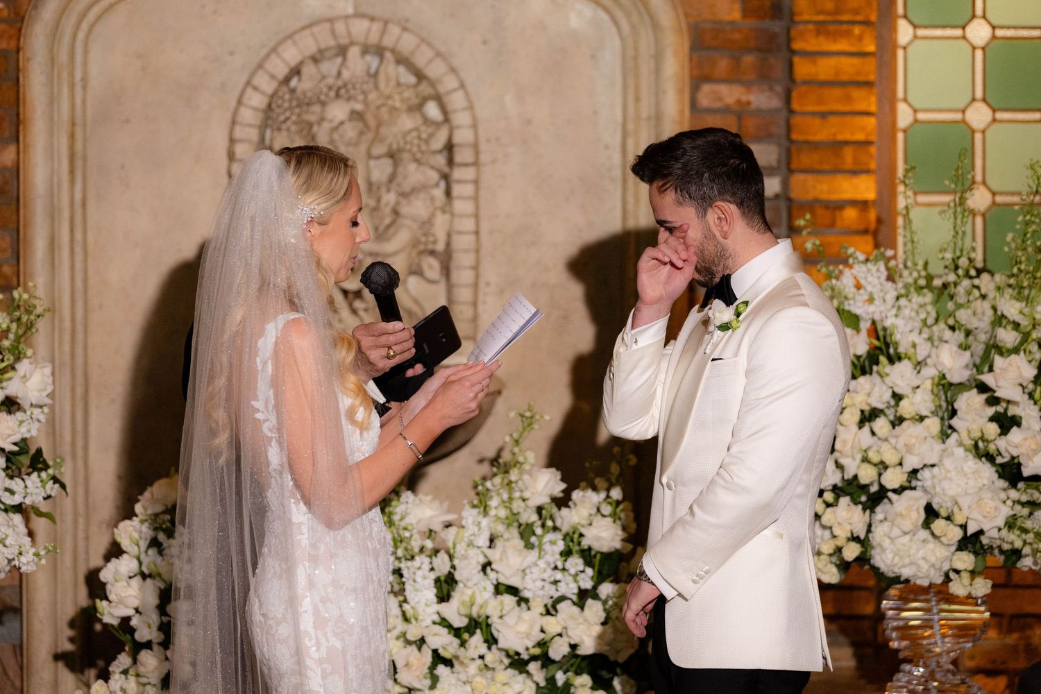 Wedding ceremony in a historic brick venue with ornate archways and floral decorations.