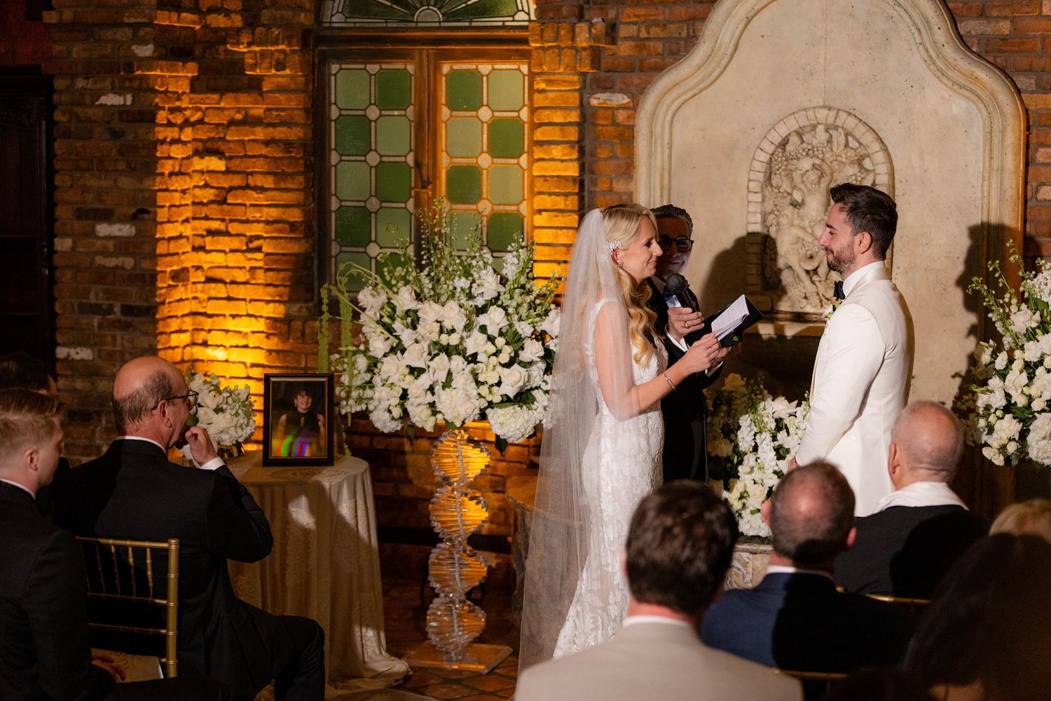 Interior of rustic brick chapel decorated with white flowers for wedding ceremony.