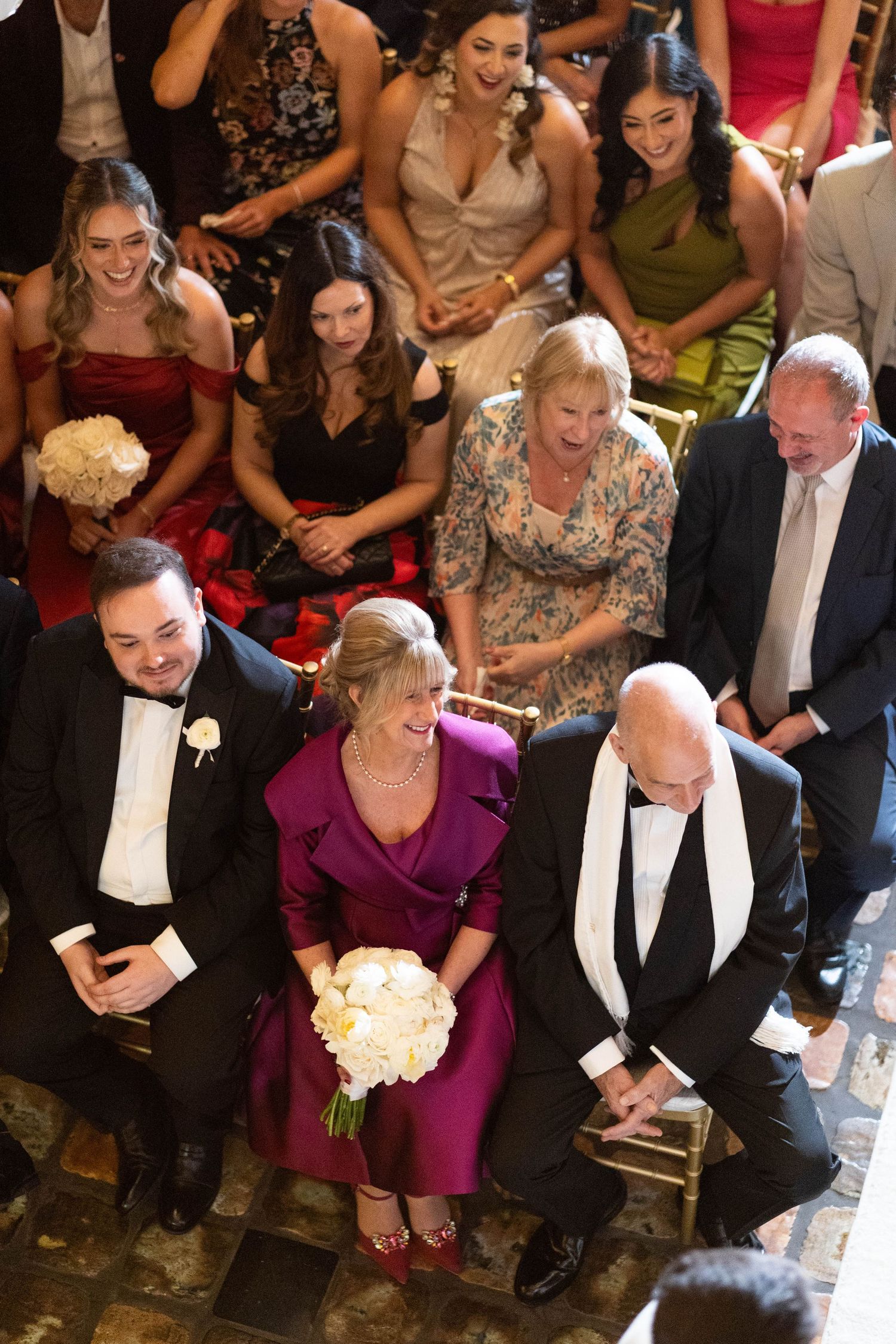 Wedding guests seated in formal attire at an elegant reception venue watching the celebration.