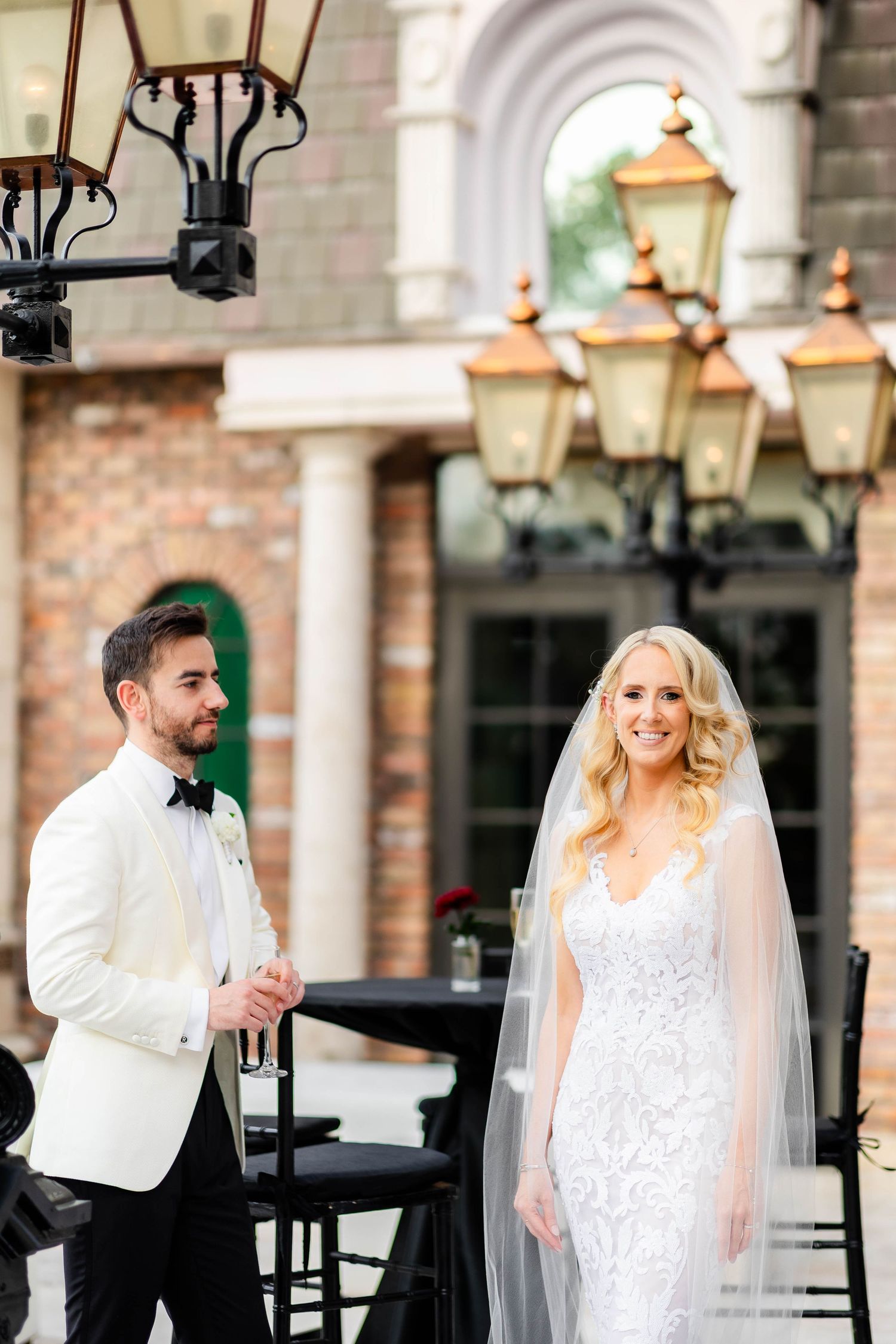 Couple shares playful moment on classic brick patio with vintage lanterns.