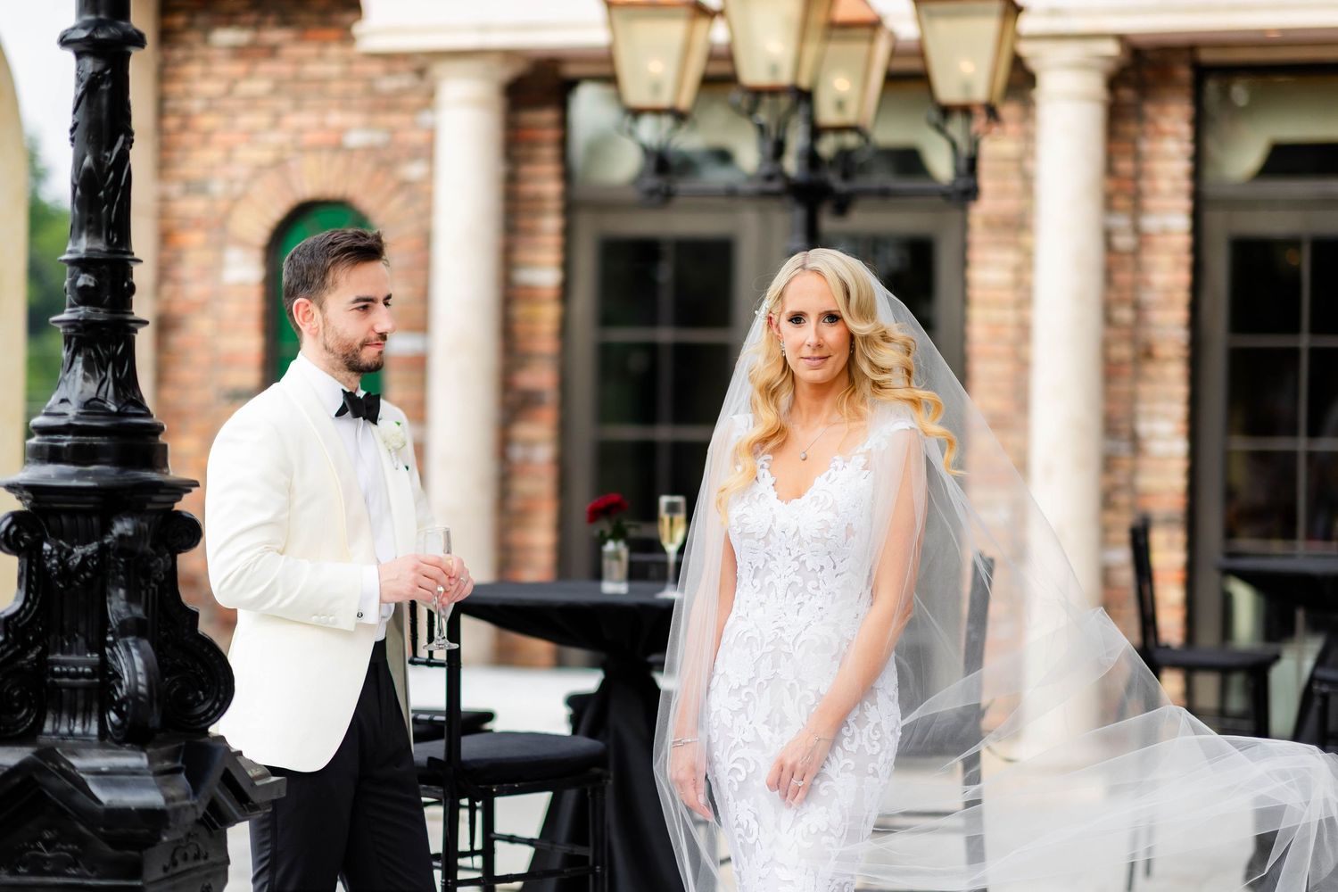 Elegant outdoor wedding venue with brick architecture and ornate lamp posts.