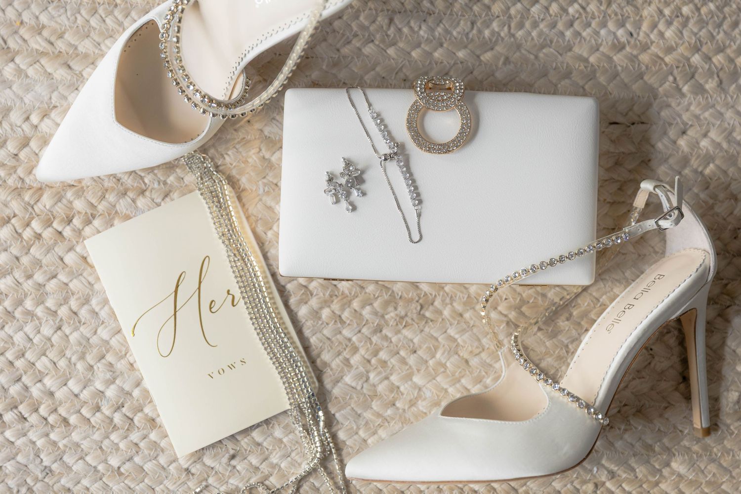 Wedding accessories including white heels and delicate invitation cards on textured background.