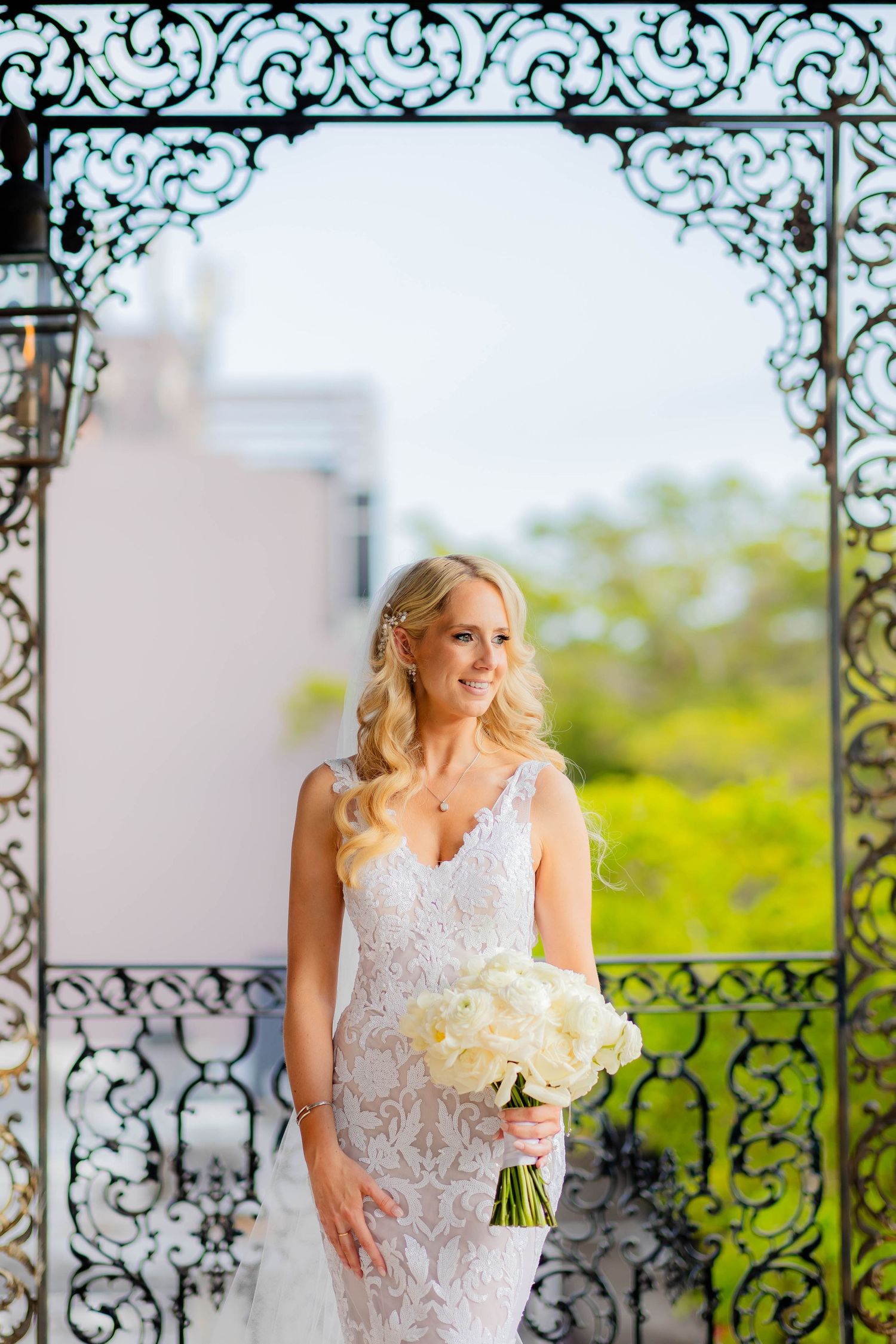 Outdoor bridal portrait under ornate iron gazebo with white floral bouquet.