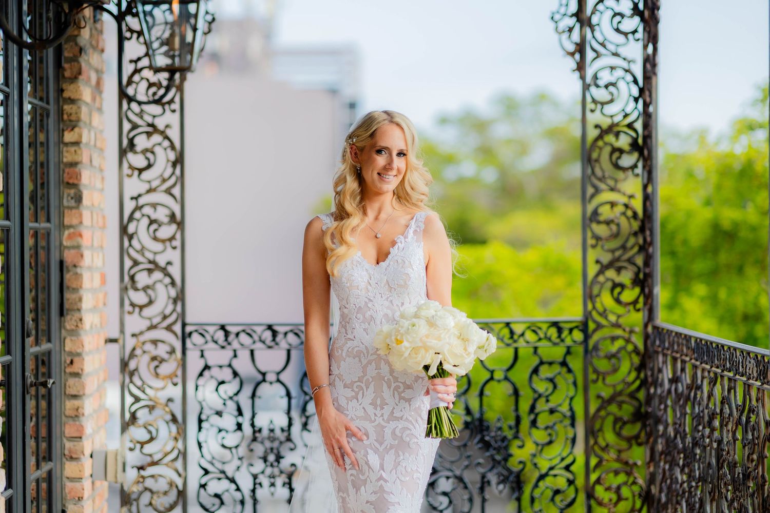 Elegant outdoor balcony with ornate iron railings surrounded by greenery.