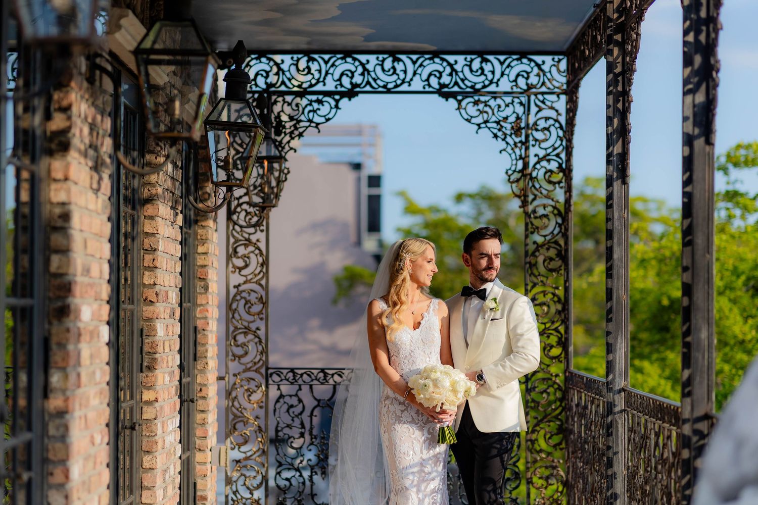 Wedding couple shares intimate moment beneath decorative iron archways.