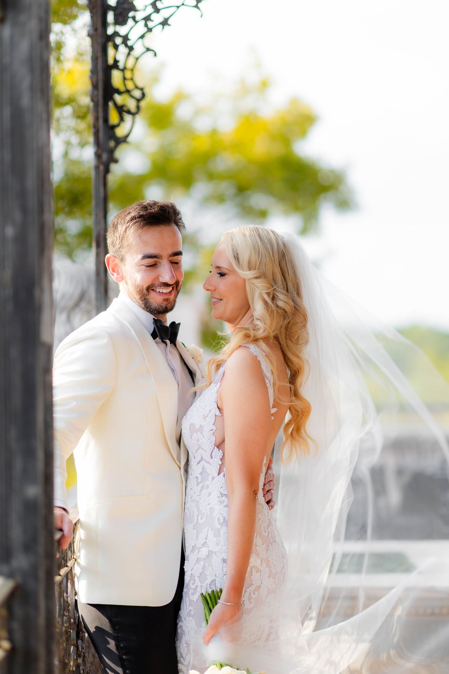 Couple shares joyful moment under decorative iron archway during wedding portraits.