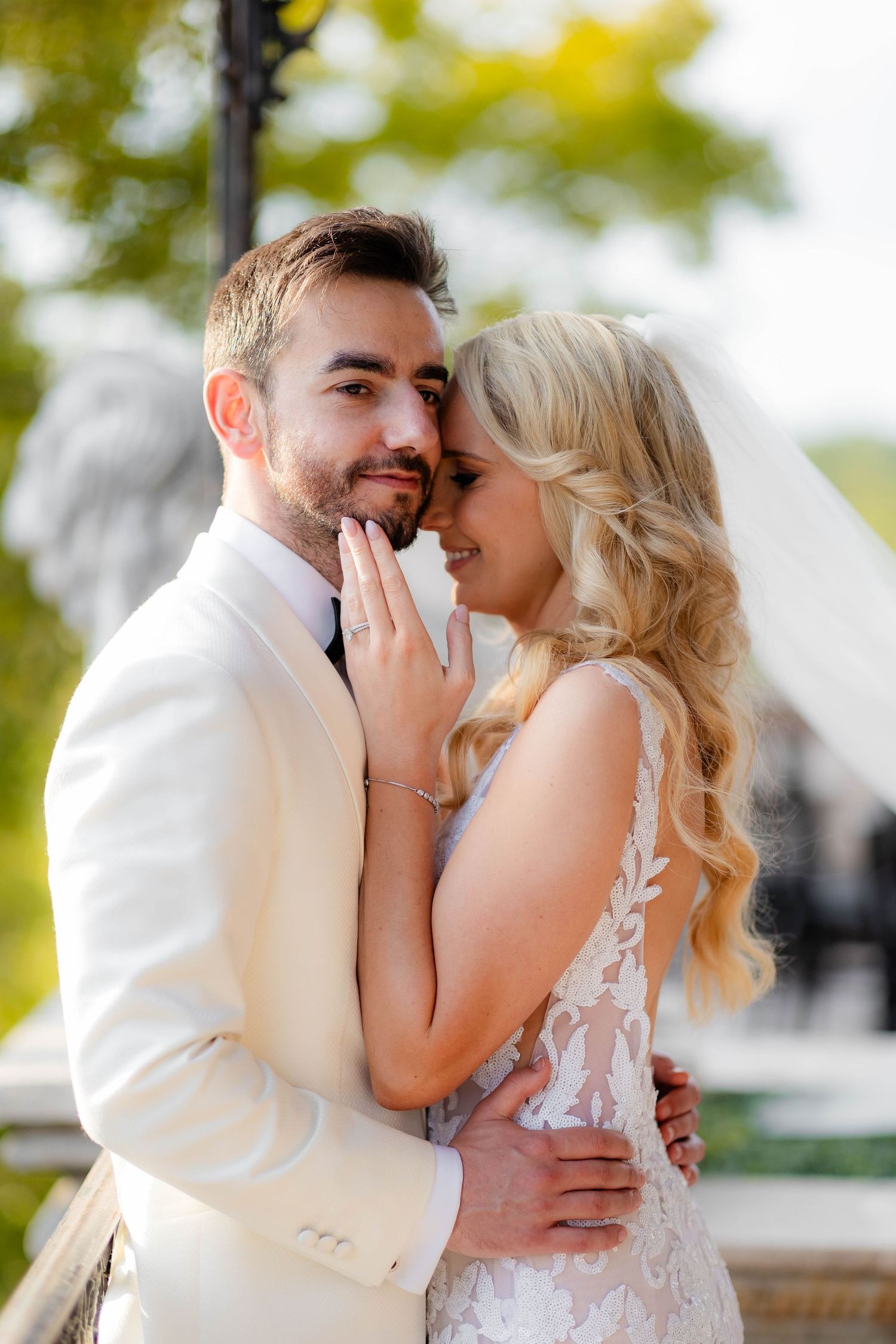 Romantic outdoor portrait of newlyweds in white attire sharing an intimate moment.
