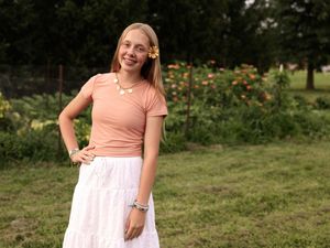 Person in peach colored top enjoying a sunny day outdoors.
