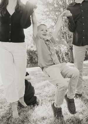 Black and white photo showing legs in white pants and dark shoes walking in a line on grass outdoors.