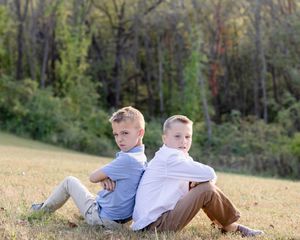 Two people lying in a grassy field on an autumn day while reading books together.