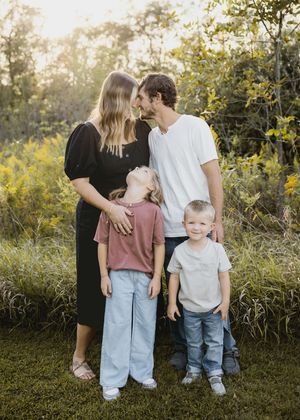 Family members stand together against backdrop of yellow wildflowers during outdoor photoshoot.