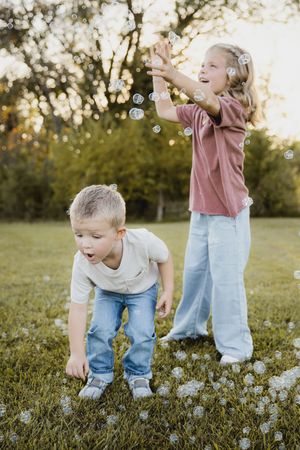 Children playing and laughing together on grass during golden hour.