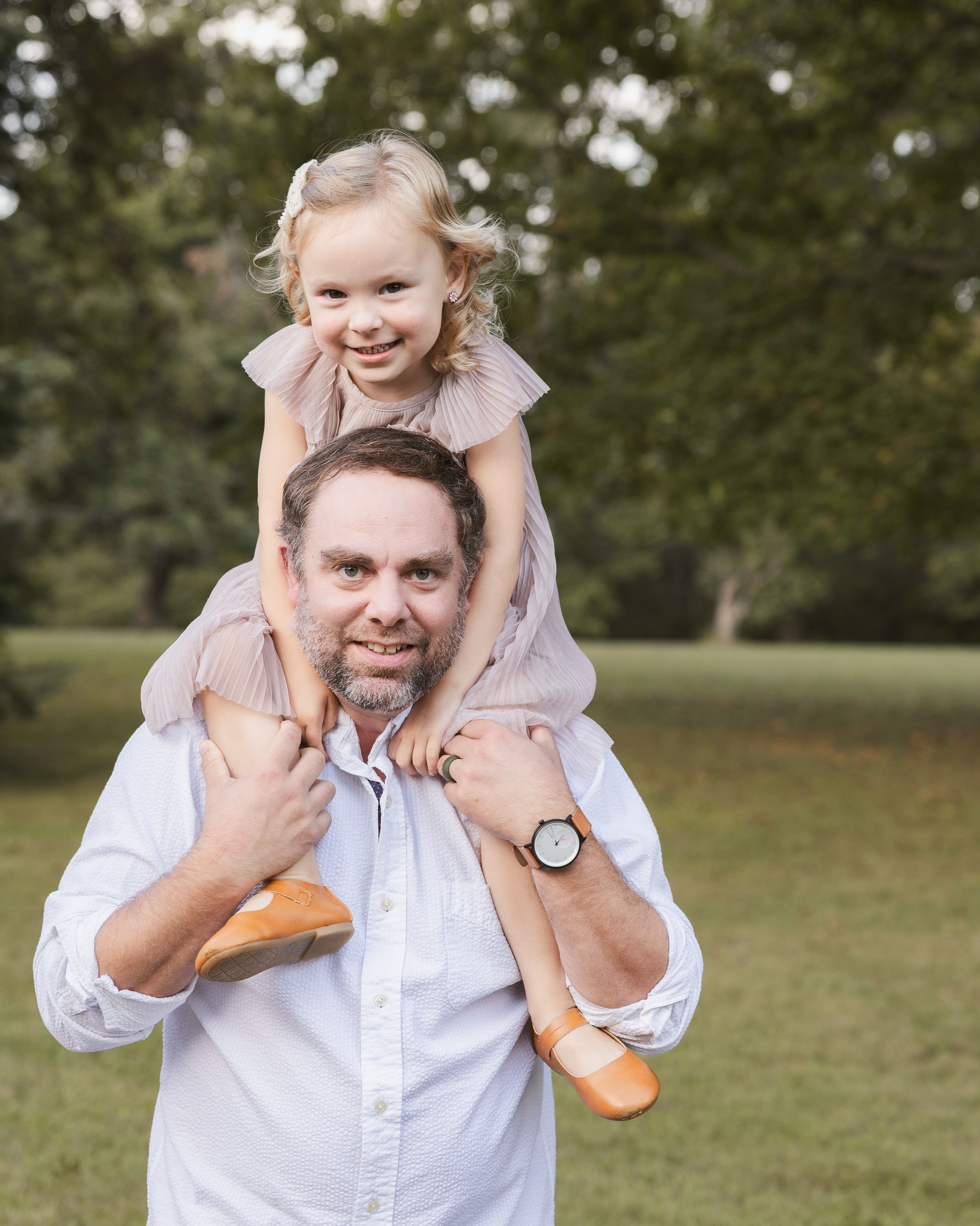 Playful shoulder rides in a sunny park setting.