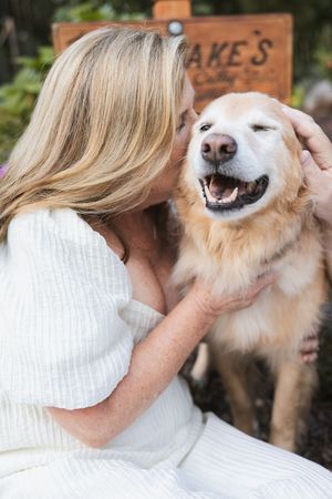 Golden retriever dog receives loving kisses while being held in a heartwarming outdoor moment.