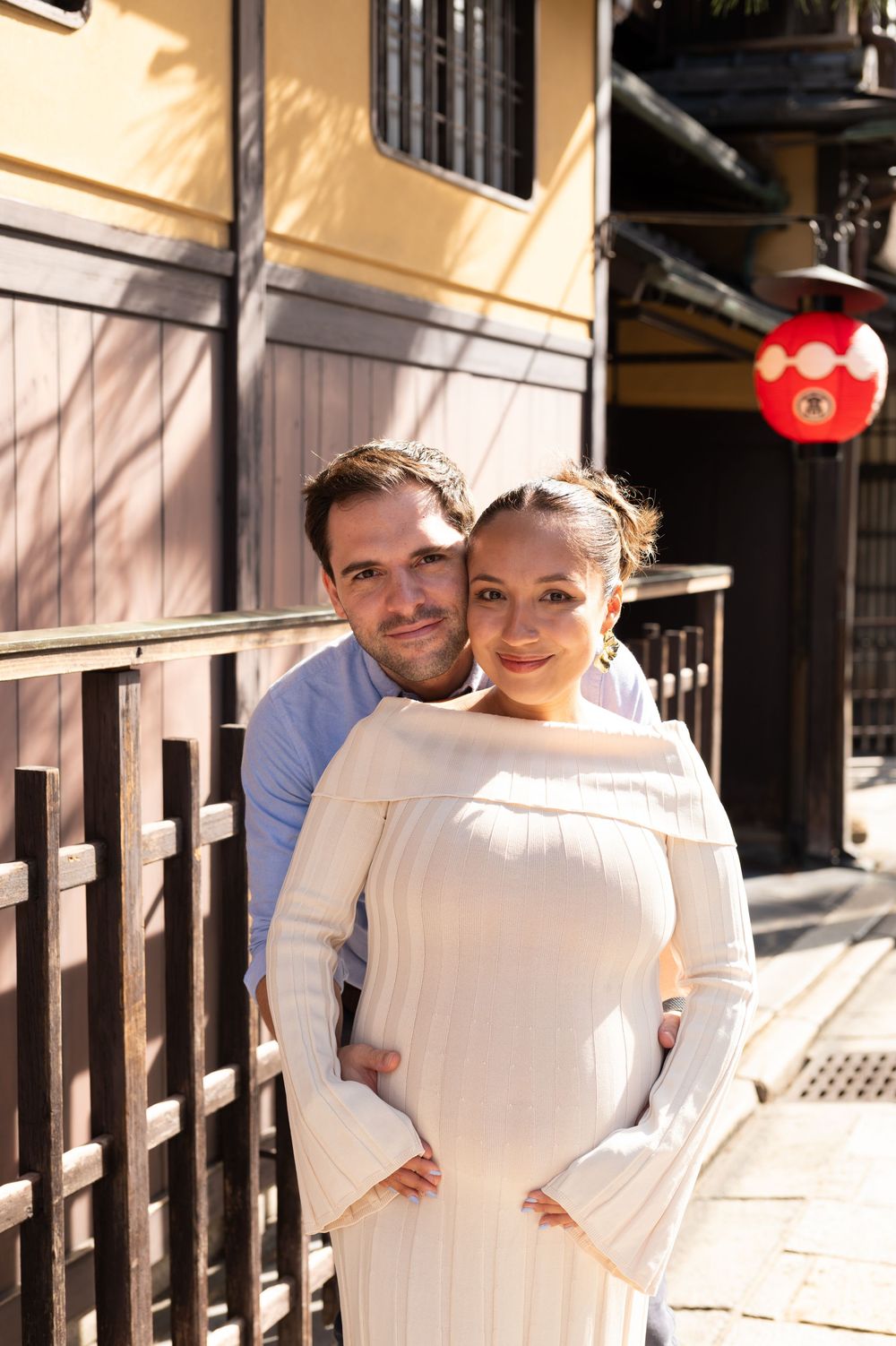 Couple poses together on a traditional Japanese street with a red lantern in the background.