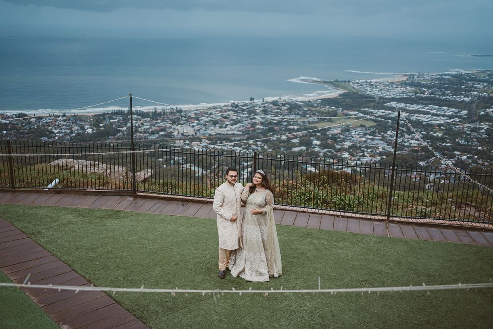 Panoramic coastal city view from a hilltop lookout with white archways in the foreground.