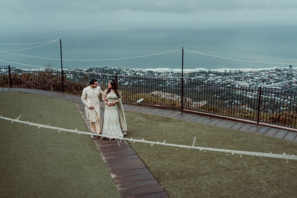 Wedding ceremony panorama at a white gazebo overlooking coastal views on a cloudy day.